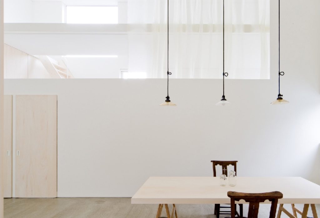 Dining table under pendant lights and high openings