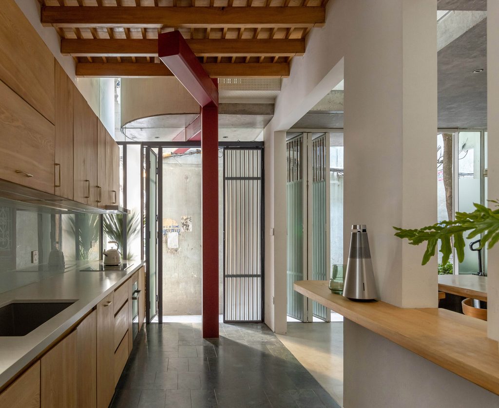 Narrow kitchen with timber cabinets and a red steel column