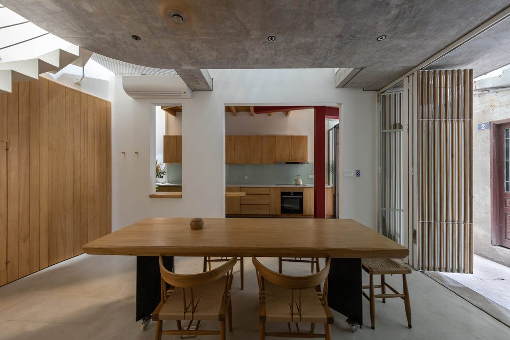 Dining table beside the kitchen and curved concrete ceiling