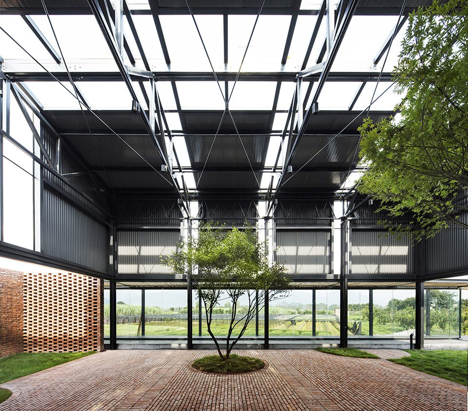 Trees and brick paving beneath exposed steel roof trusses