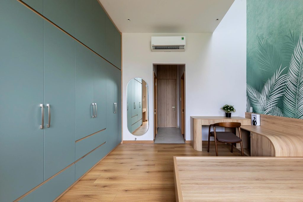 Bedroom with green wardrobes and timber flooring