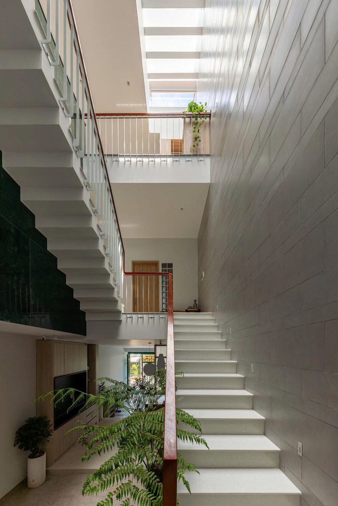 White staircase rising beside a tall pale brick wall
