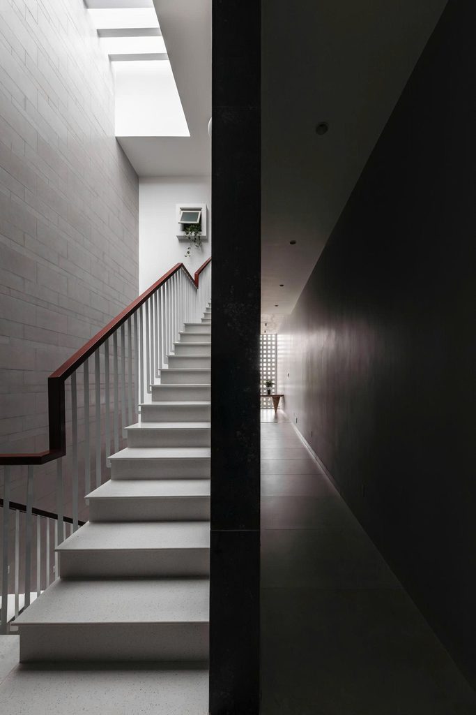 Staircase beneath a rooflight beside a pale masonry wall
