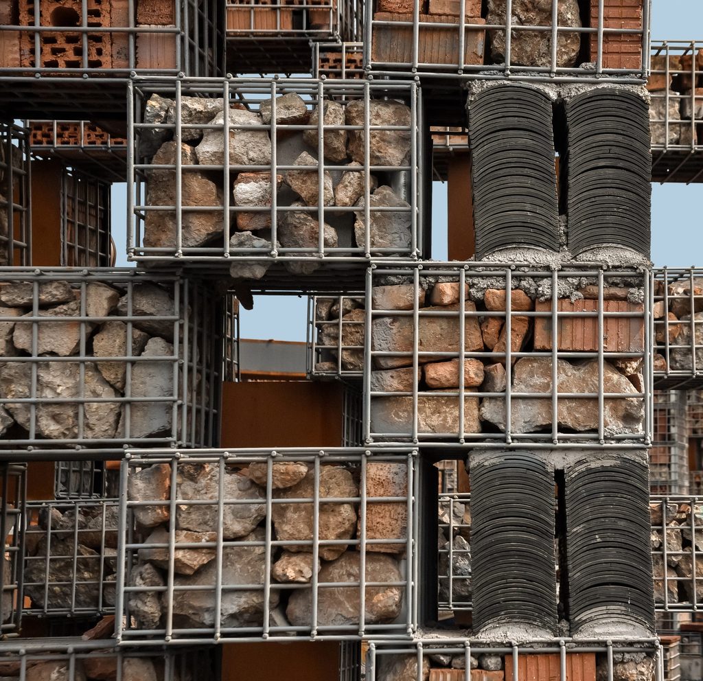 Reused bricks and tiles packed into a steel facade cage