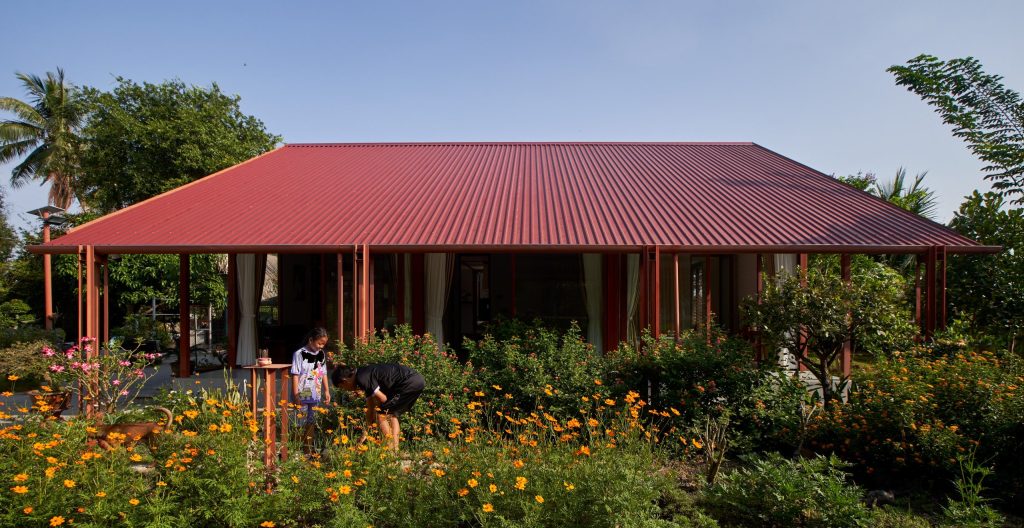 Garden House by aha.studio.arc, Go Quao, An Giang, the house behind its flower garden by day