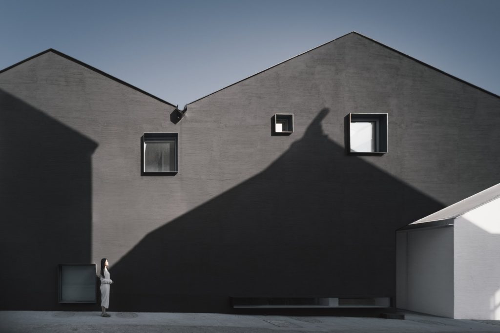 Dark gabled volumes with a single small window