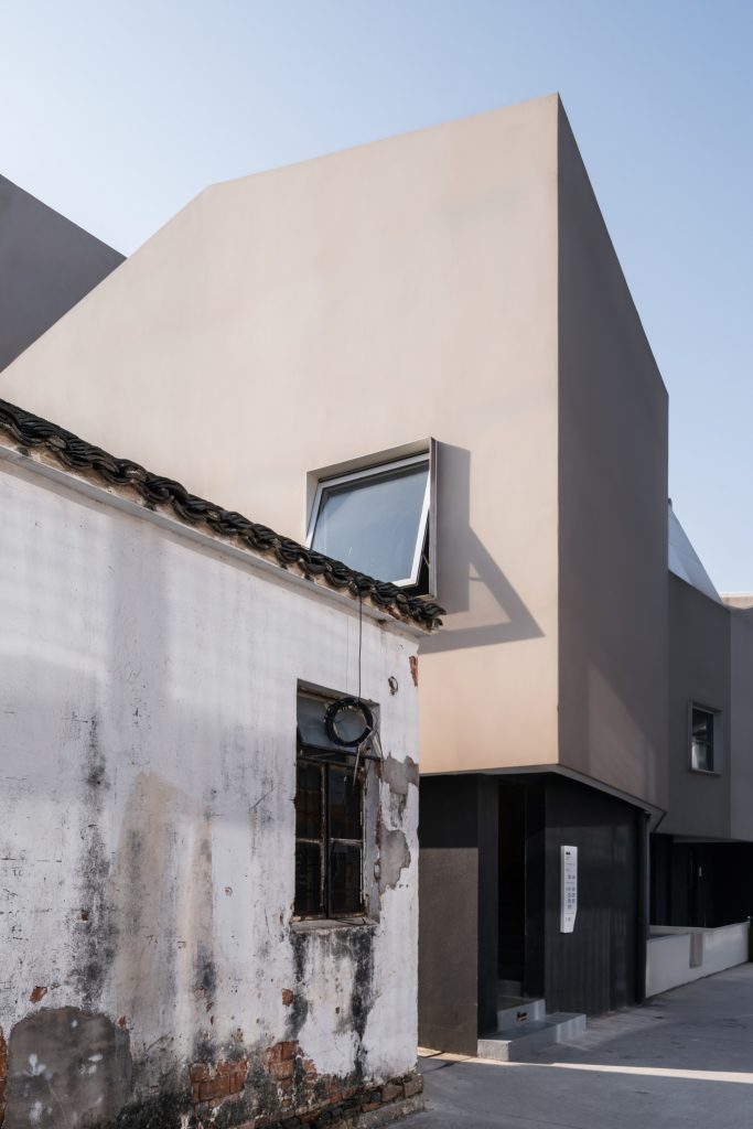 Old plastered wall against the new faceted facade