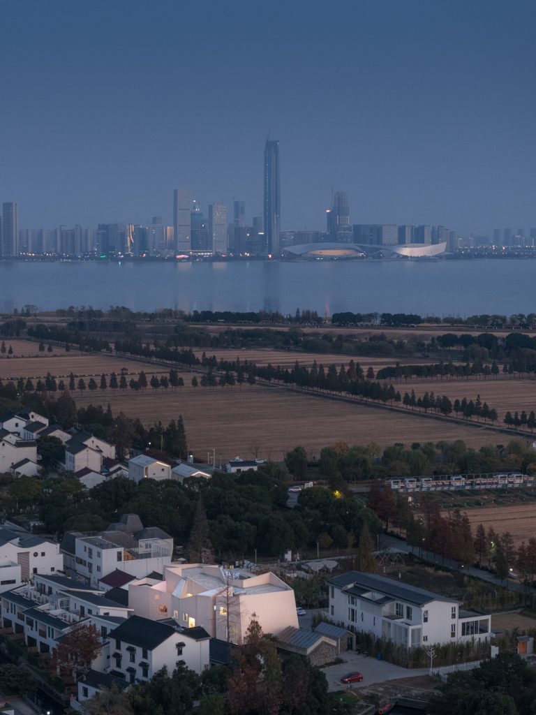The village at dusk with a distant city skyline across the lake