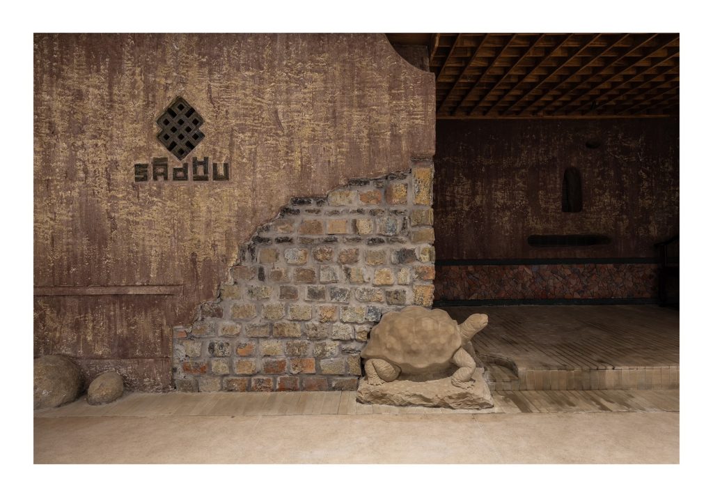 Entrance wall of stacked old tiles around the Sadhu sign