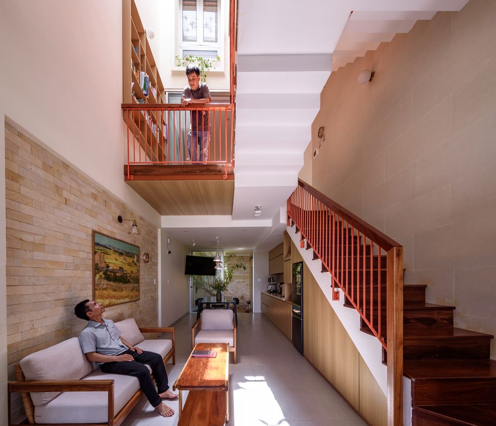 The long living room and kitchen beneath an upper landing and timber staircase