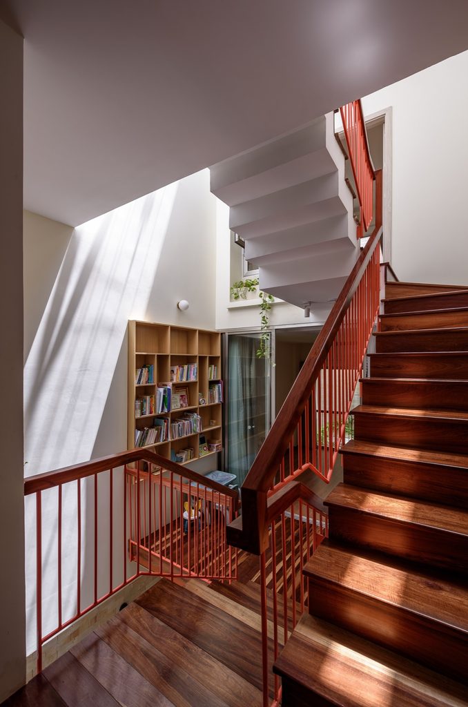 Timber stair flights and red metal railings connect the split levels