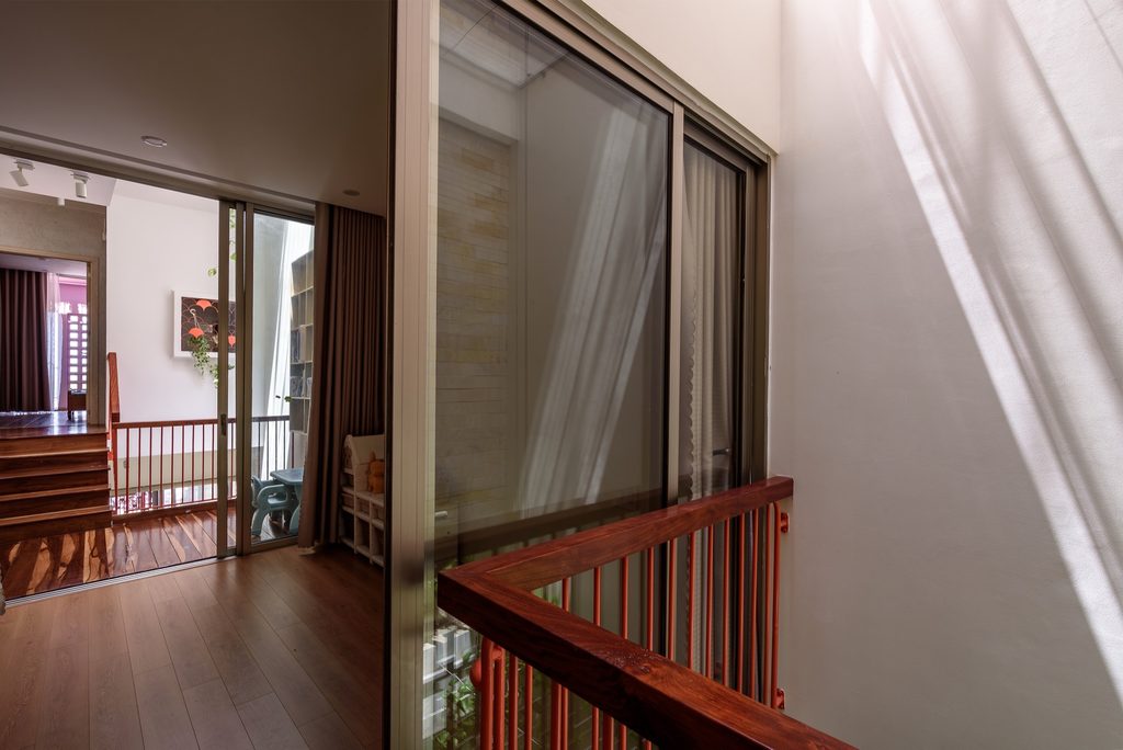 Sliding glass doors open onto the upper landing beside a red metal rail