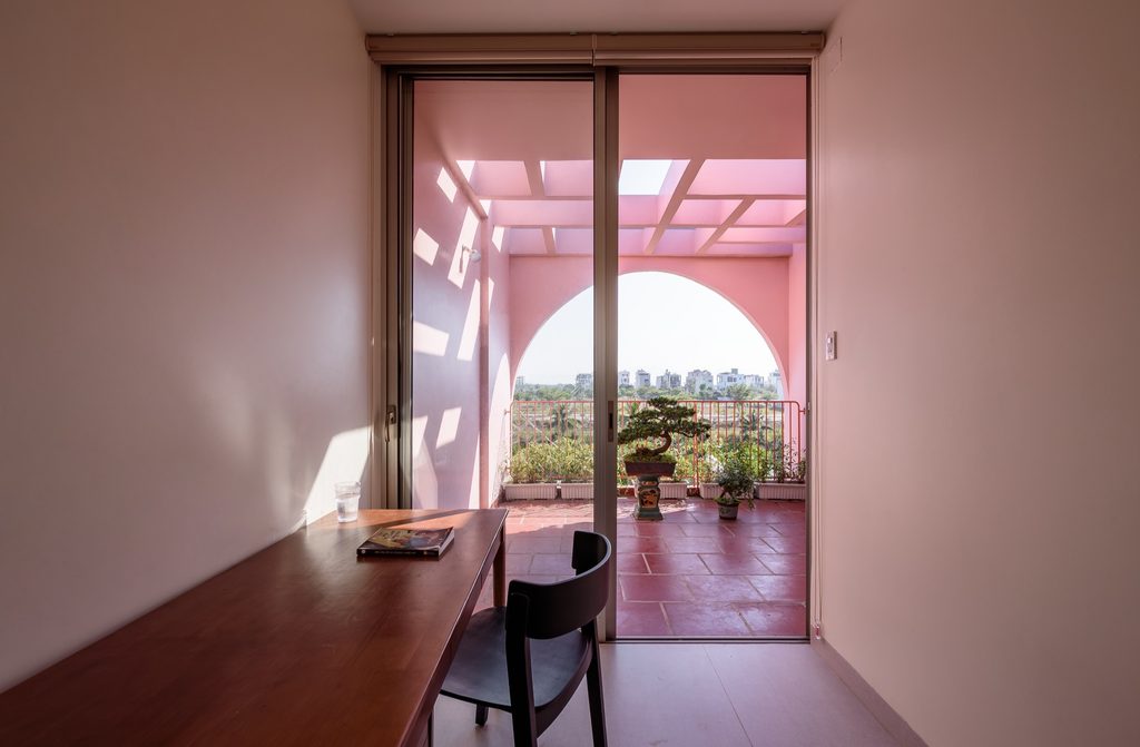 A small work table faces the rooftop terrace through an arched opening