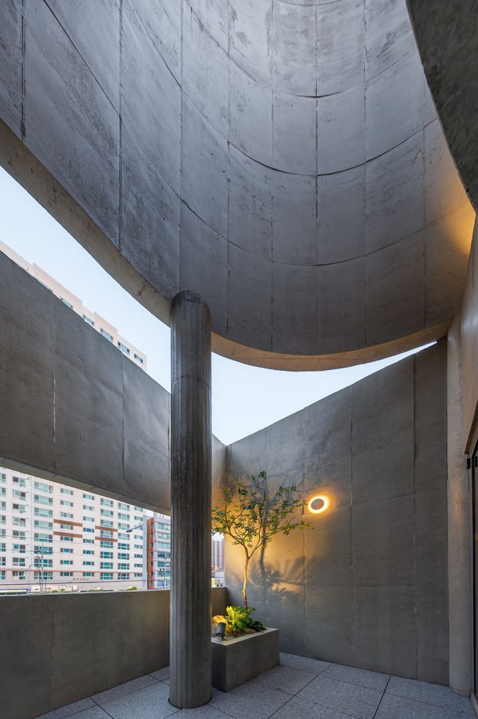 Sheltered terrace beneath a curved concrete canopy