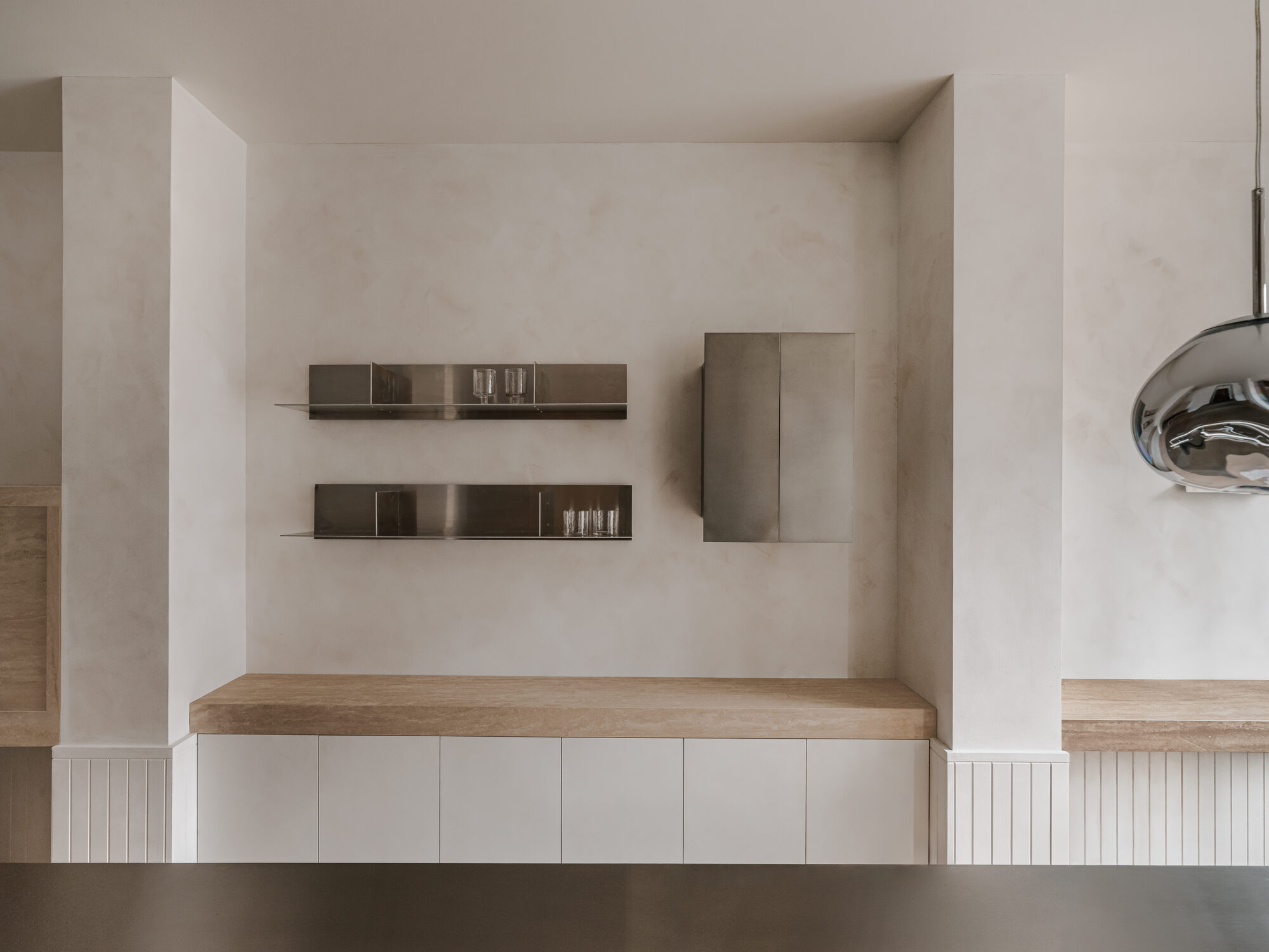 Mediterranean apartment pairs oak joinery with travertine and steel