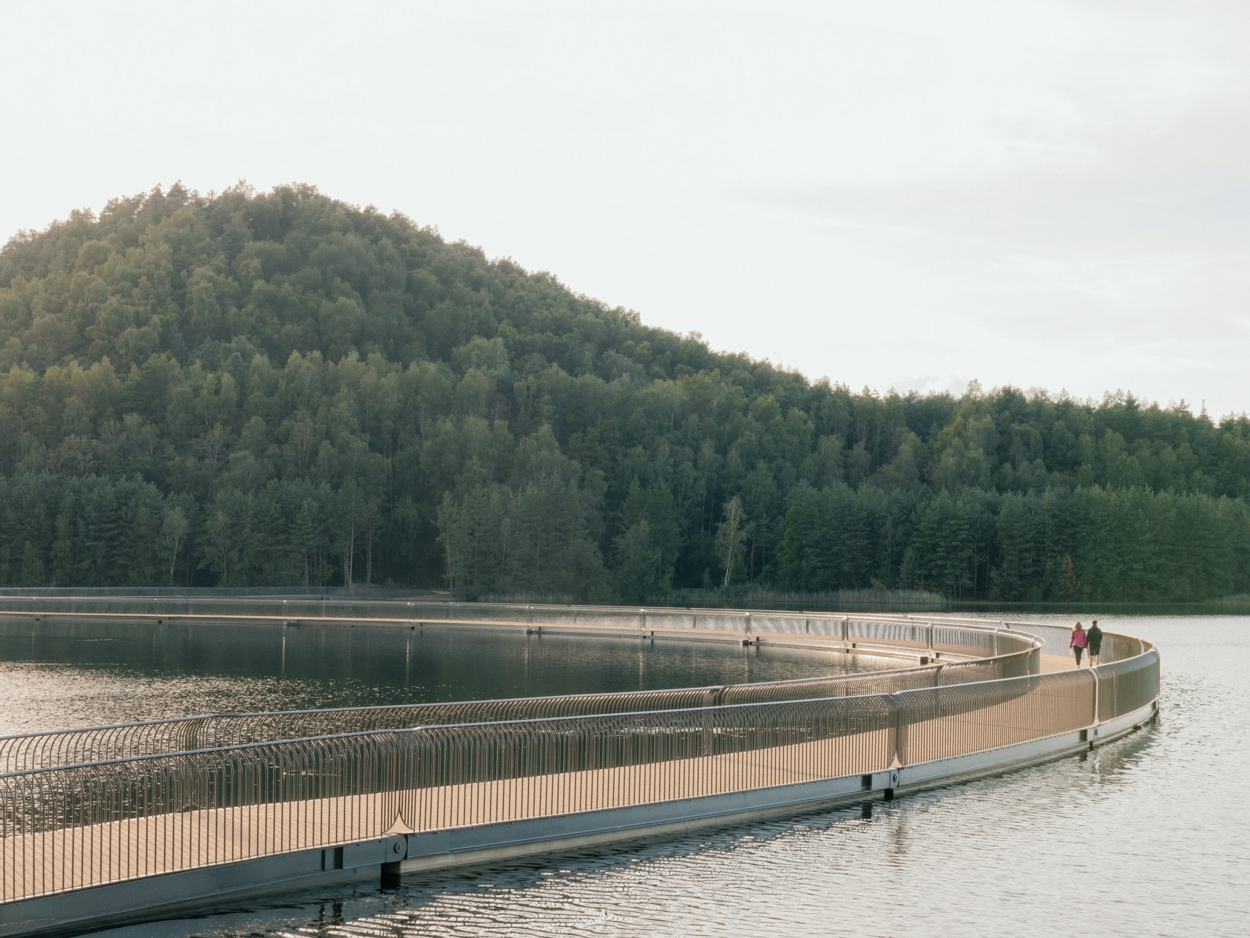 Cyclists crossing the floating bridge between mining terrils in Belgium