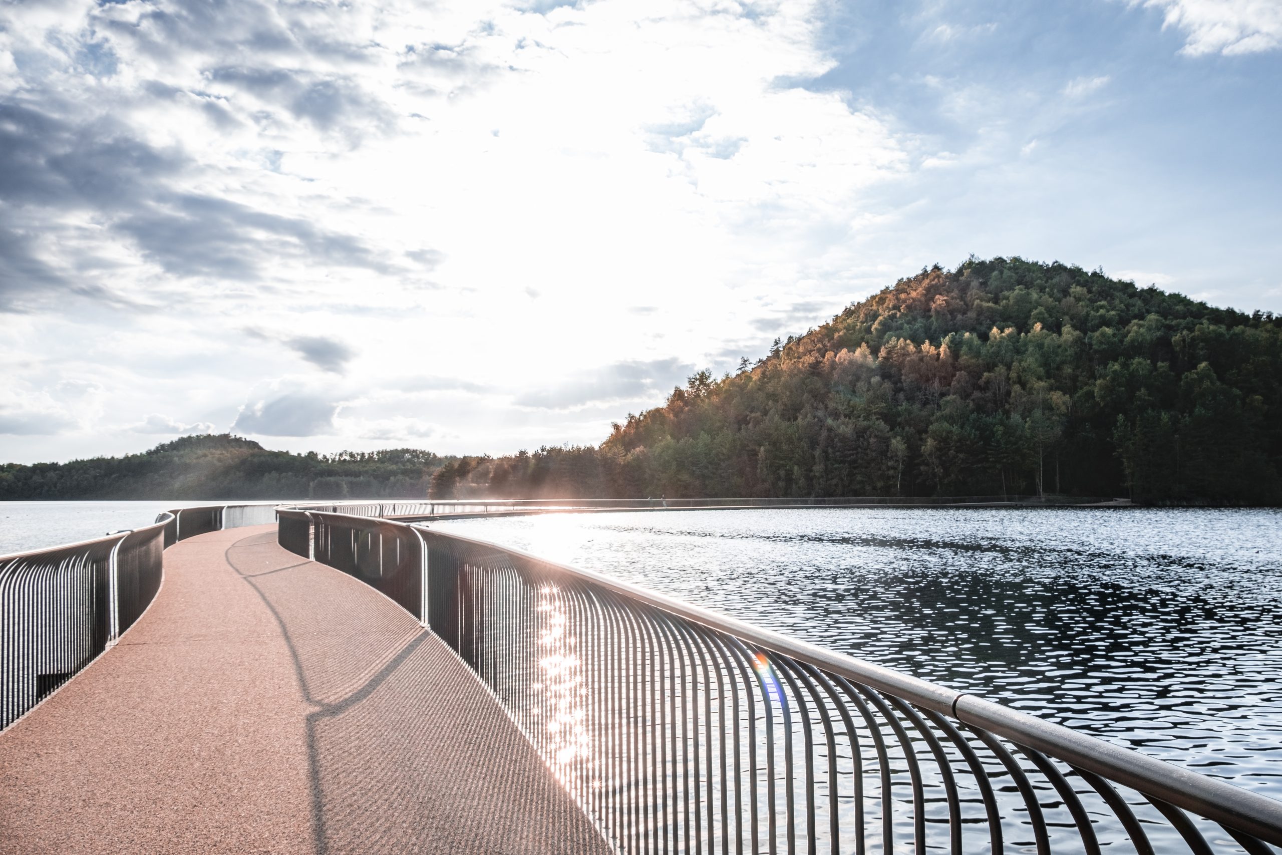 Curved floating bridge across water at Terhills in Limburg