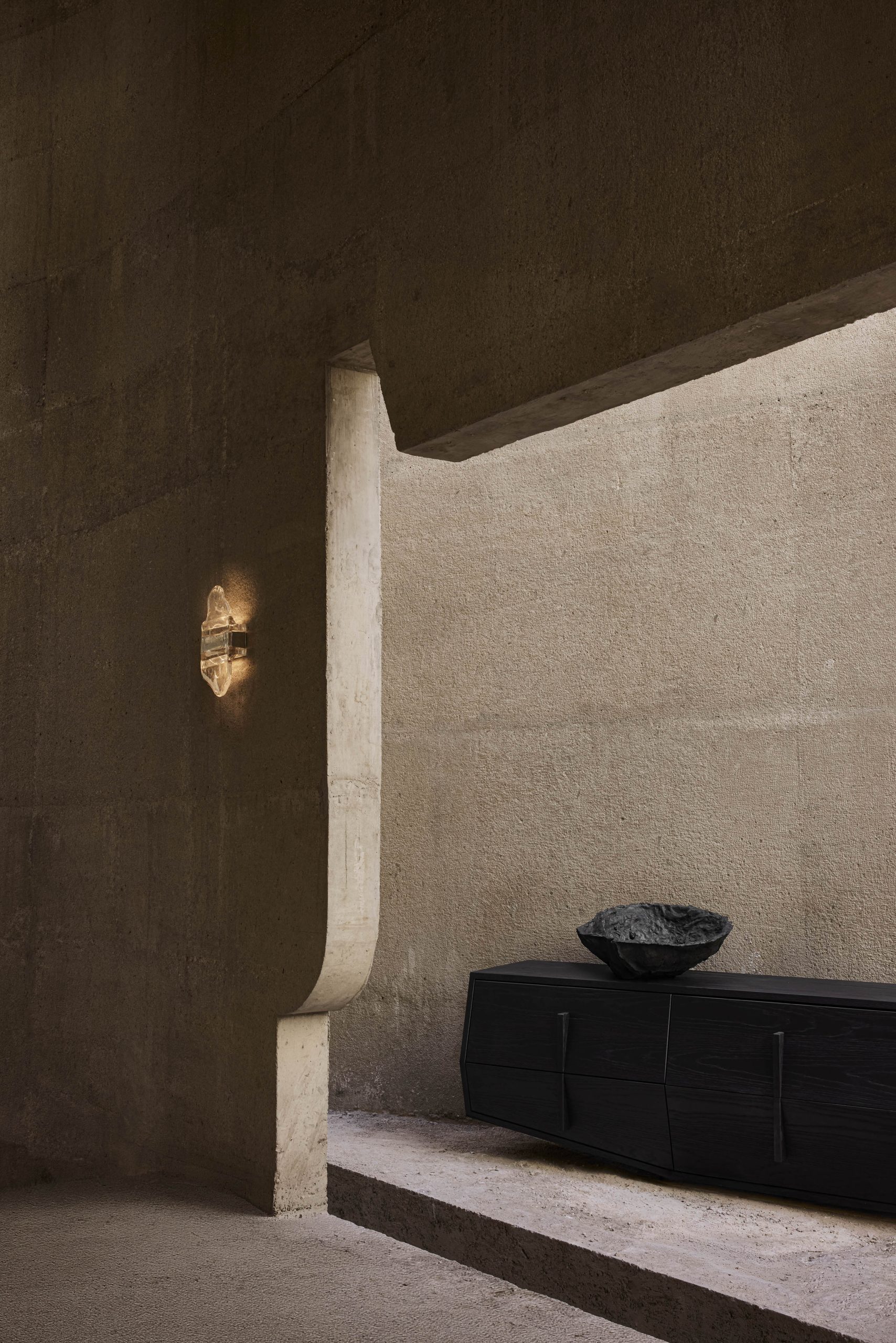 Curved concrete opening and dark seating inside Casa Ínsula