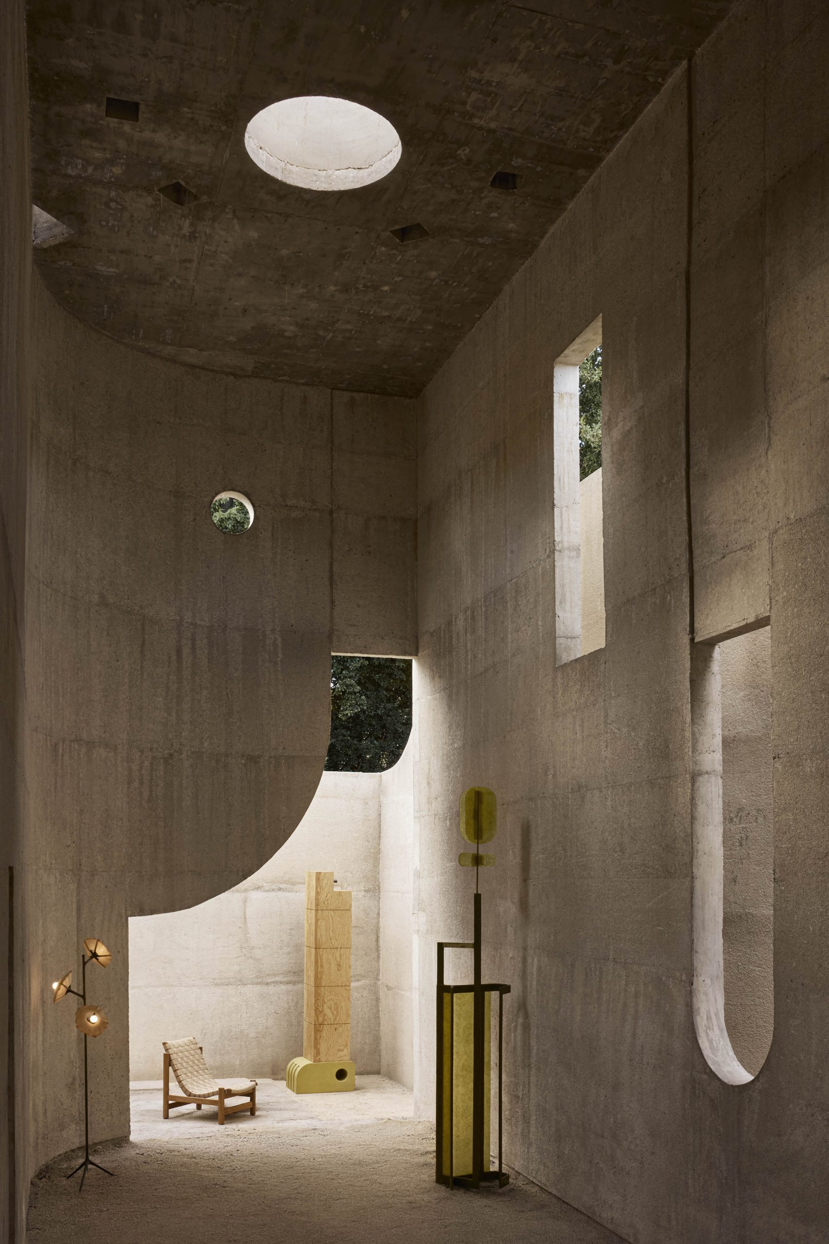 Tall concrete room lit through circular and vertical openings at Casa Ínsula