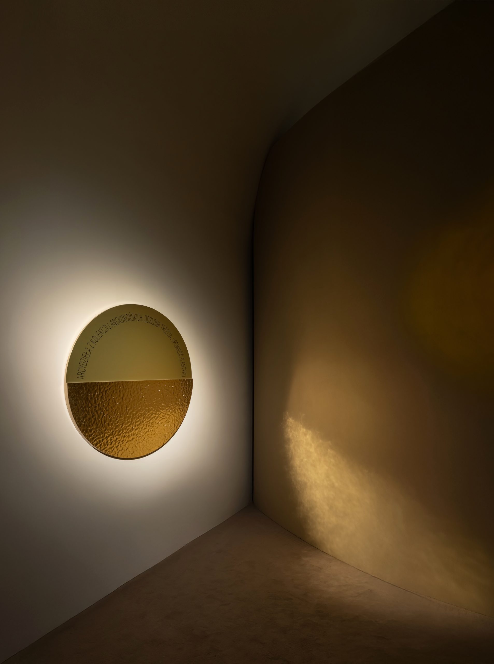 Ancient sculpture displayed against curved birch plywood walls