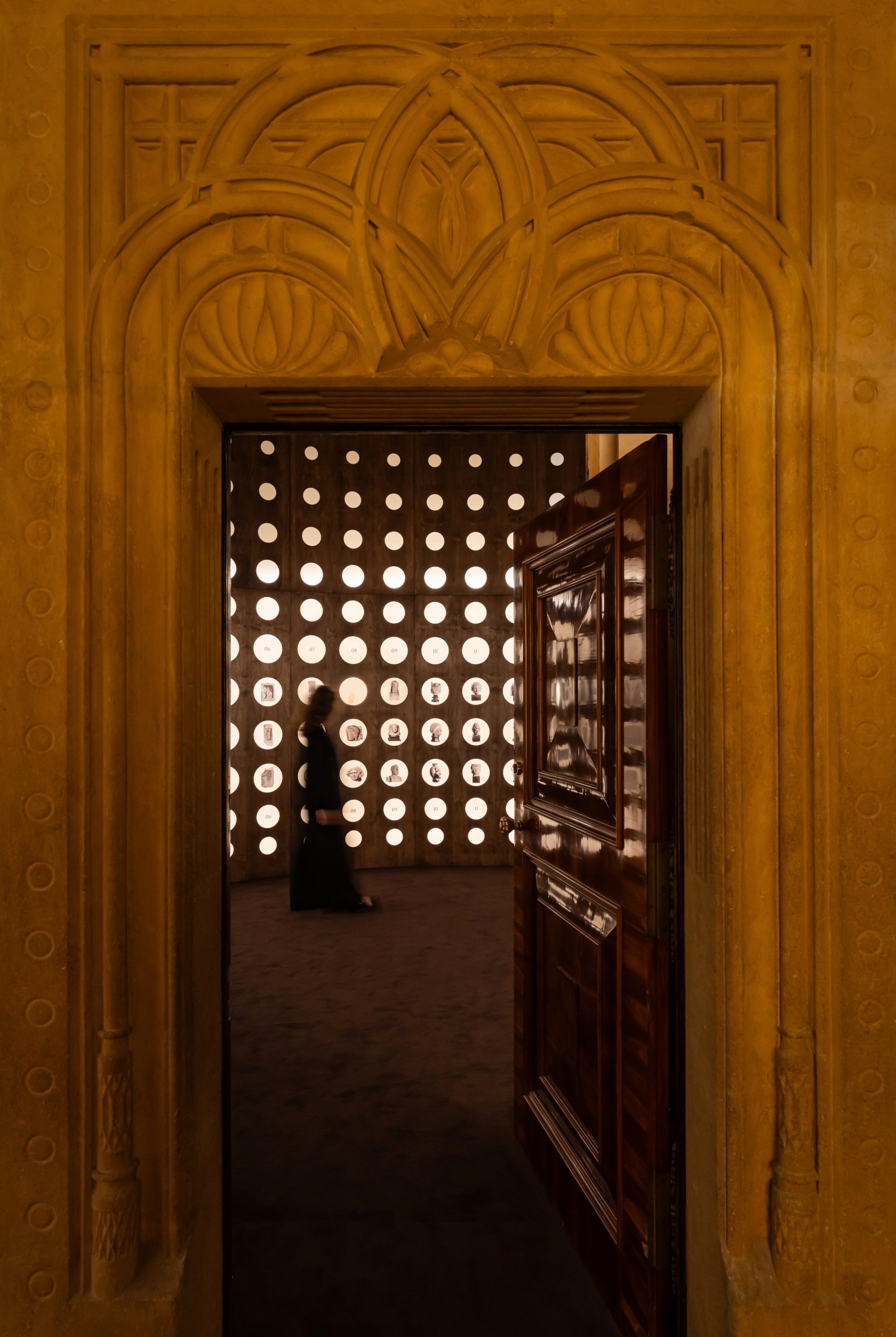 Circular openings display photographs and artefacts in a brown gallery