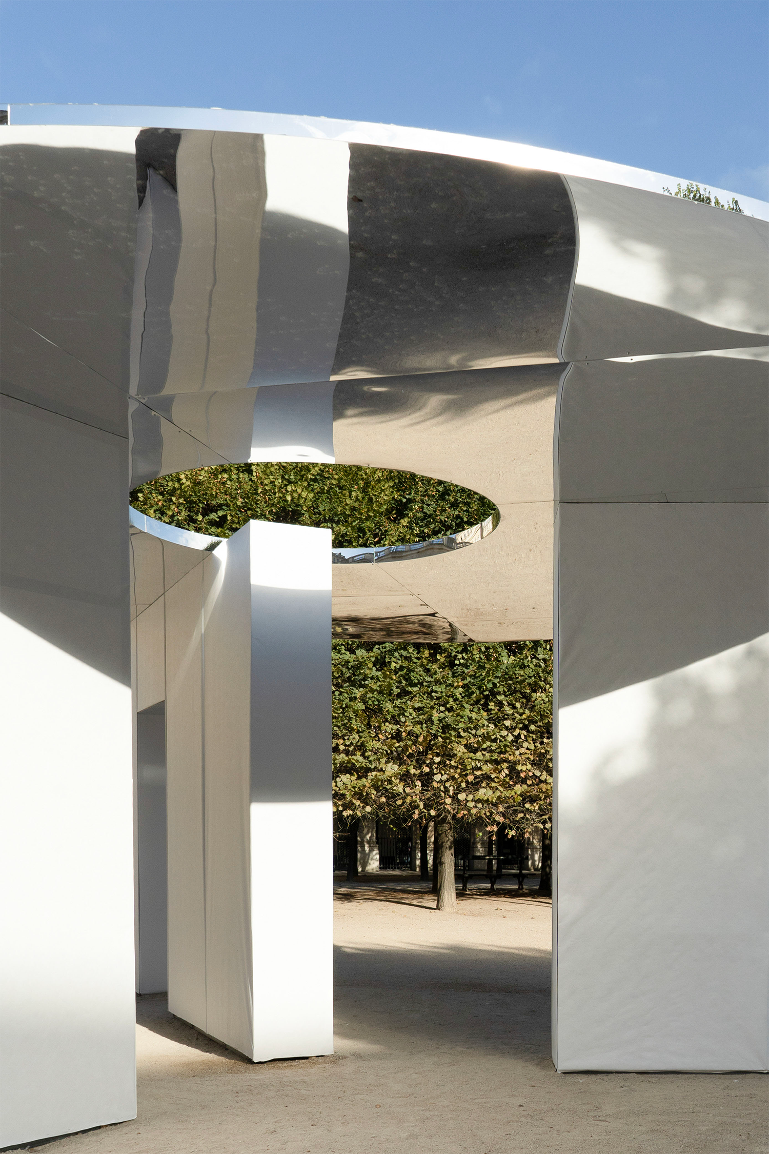 Reflections extend the walls and surrounding greenery across the roof.
