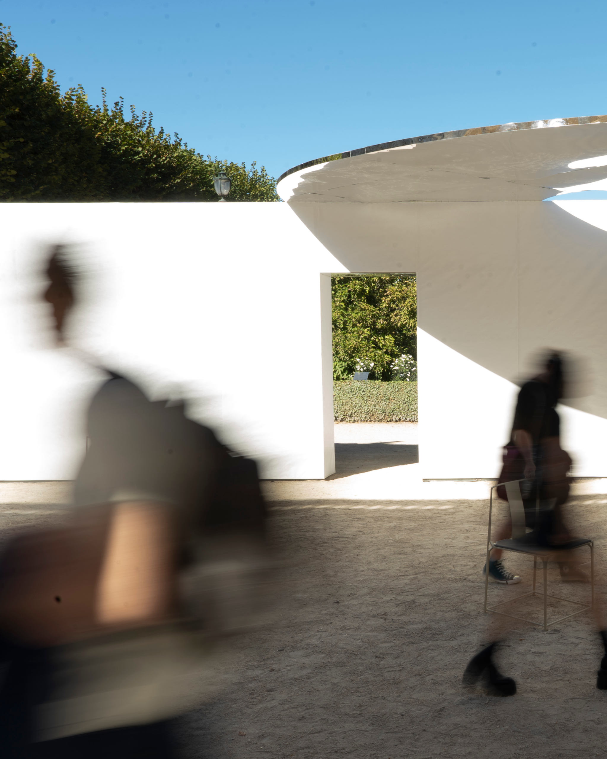 Visitors move through apertures in the pale walls.