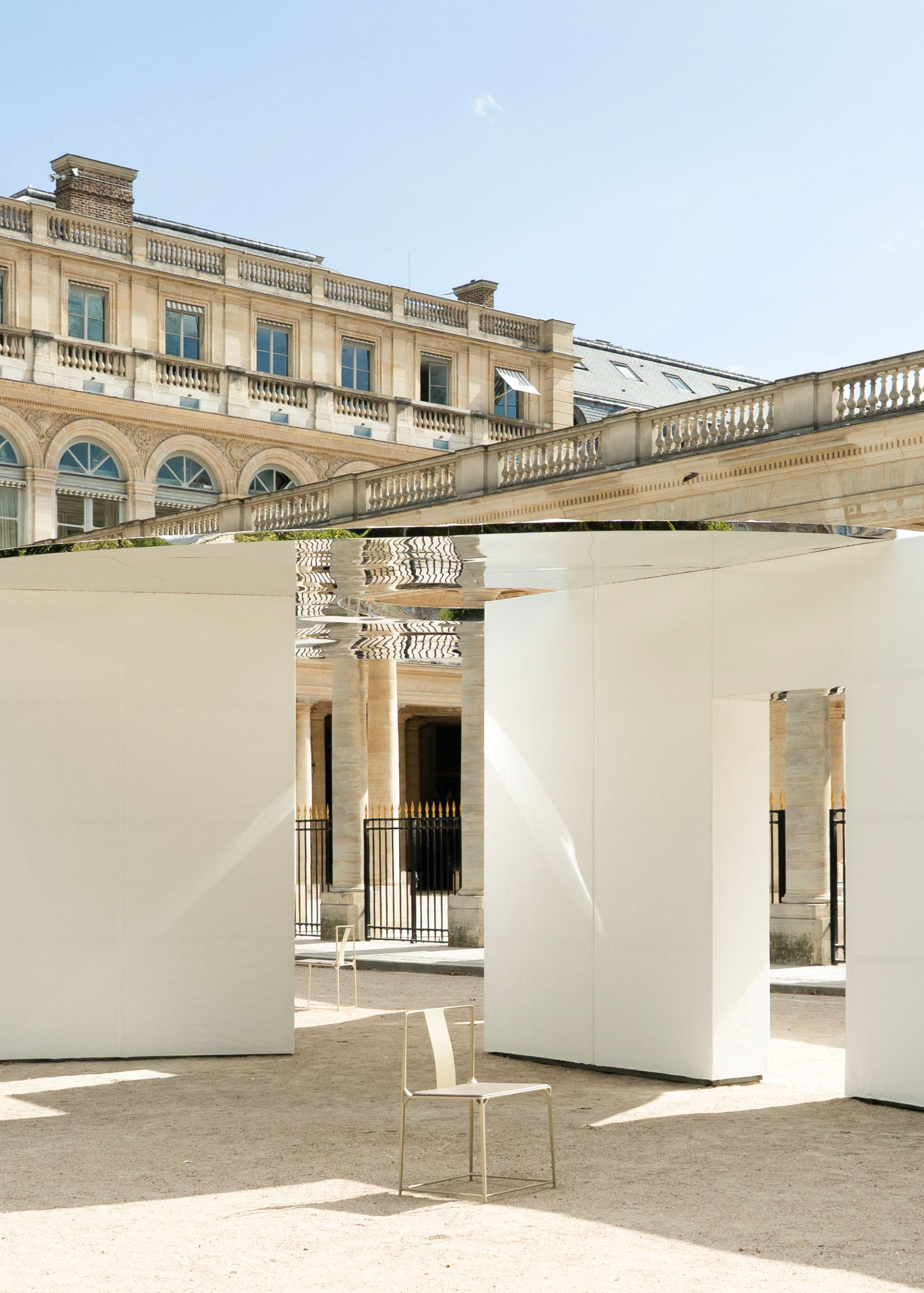 Three walls of different lengths sit beneath a circular mirrored roof.