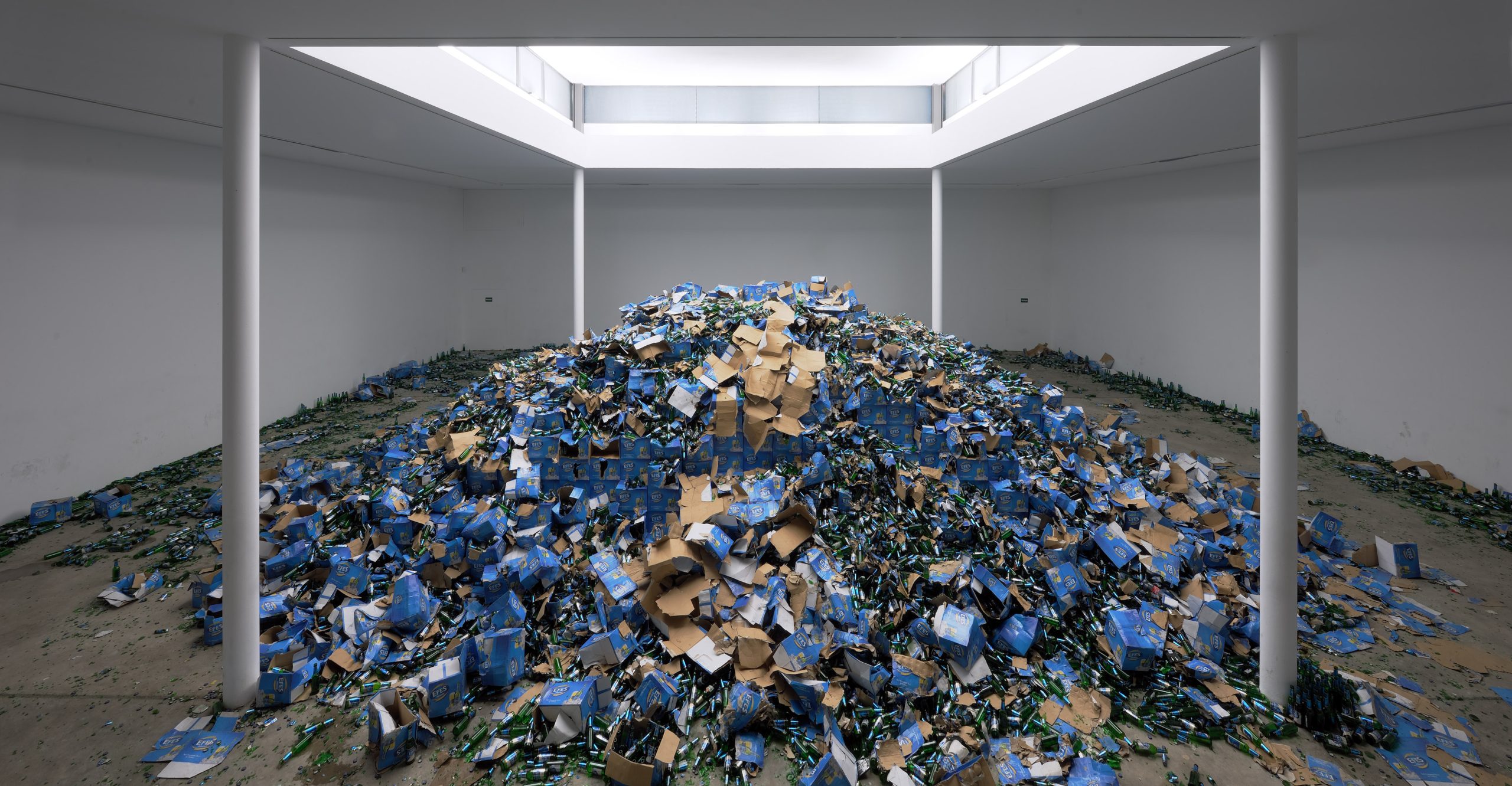 Torn cardboard exposes brown surfaces among the blue cartons.