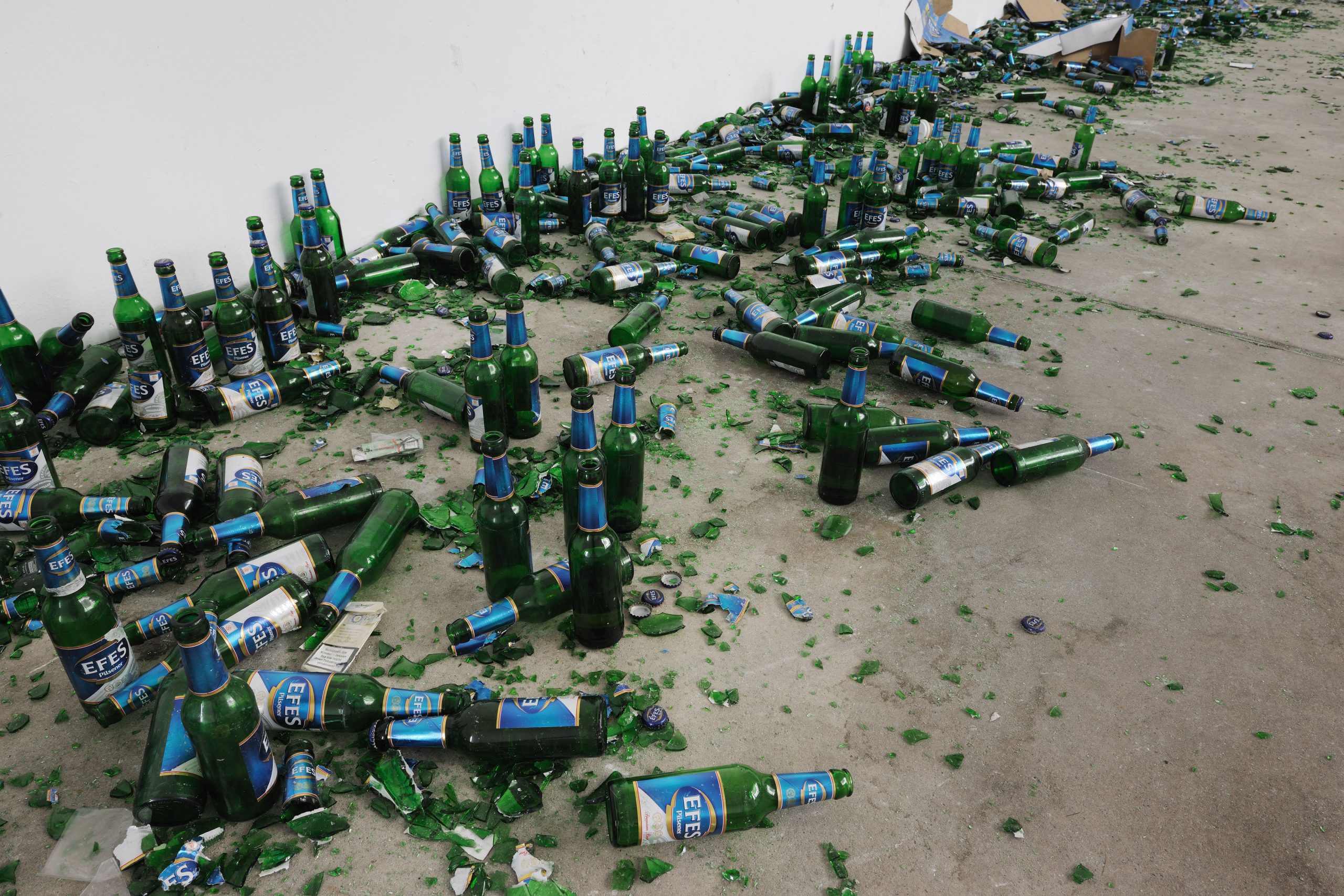 Green glass bottles and fragments spread along the gallery wall.