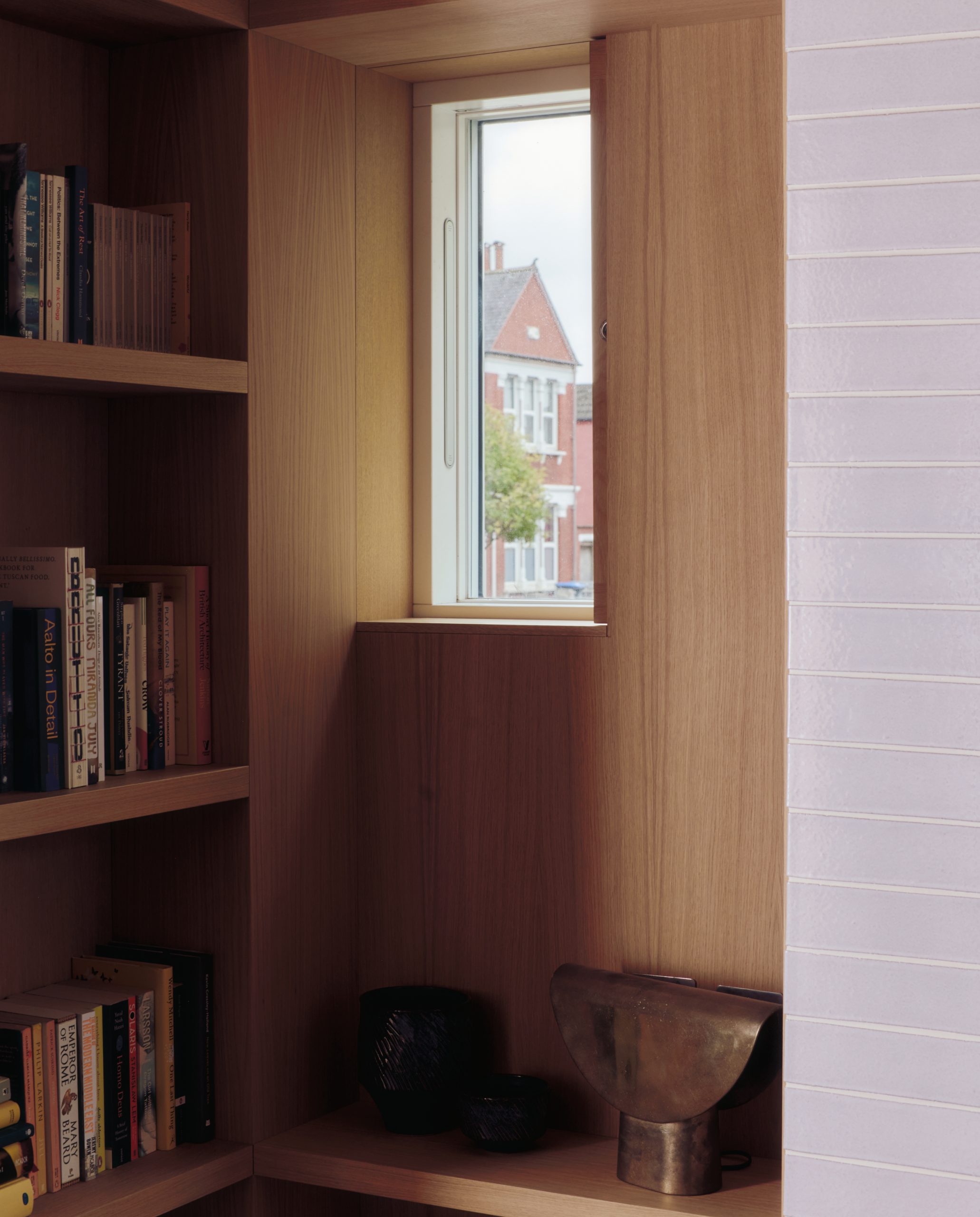 A bespoke timber shutter controls the street-facing library window.