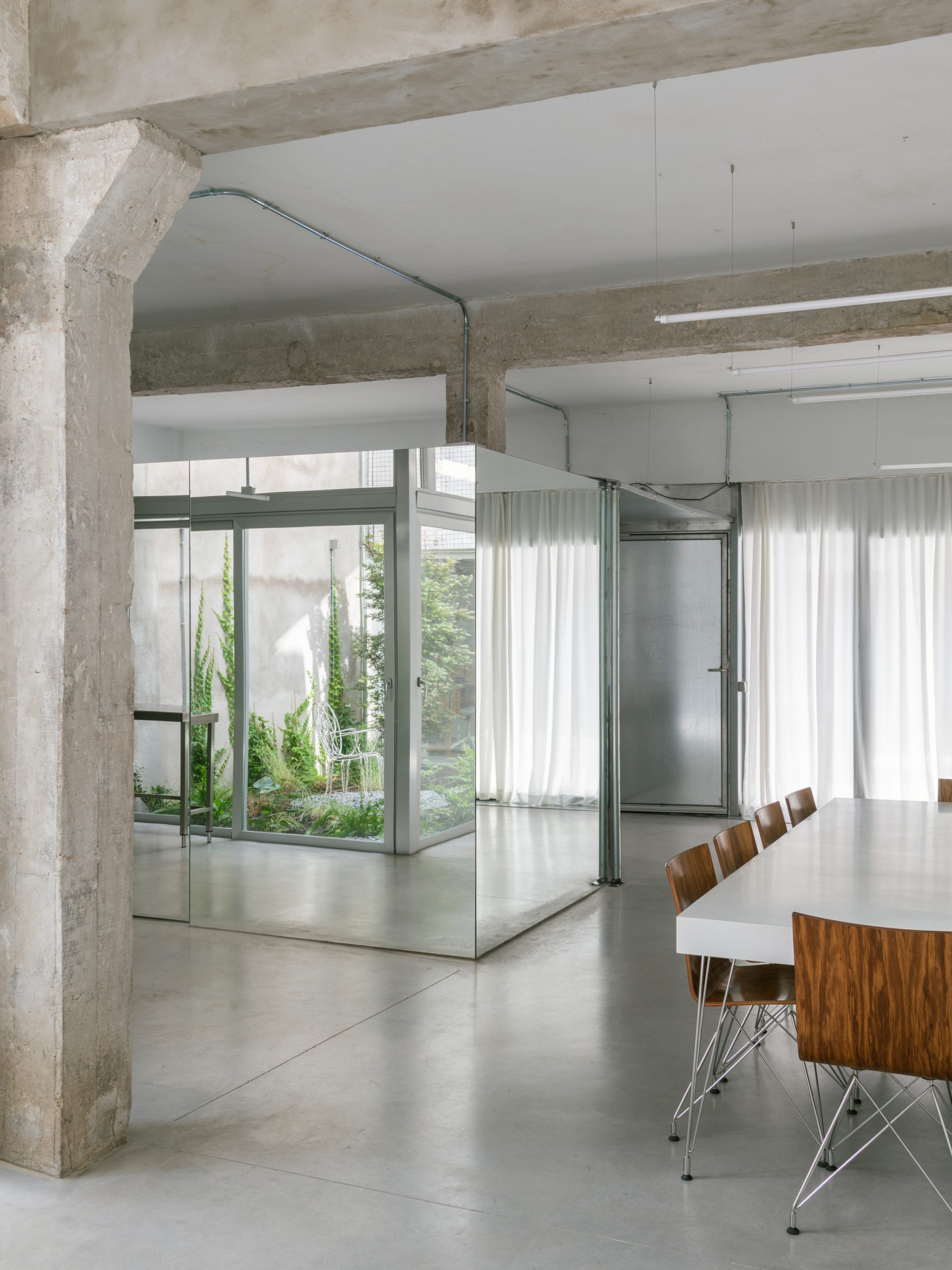 The mirrored enclosure reflects the courtyard into the hall.