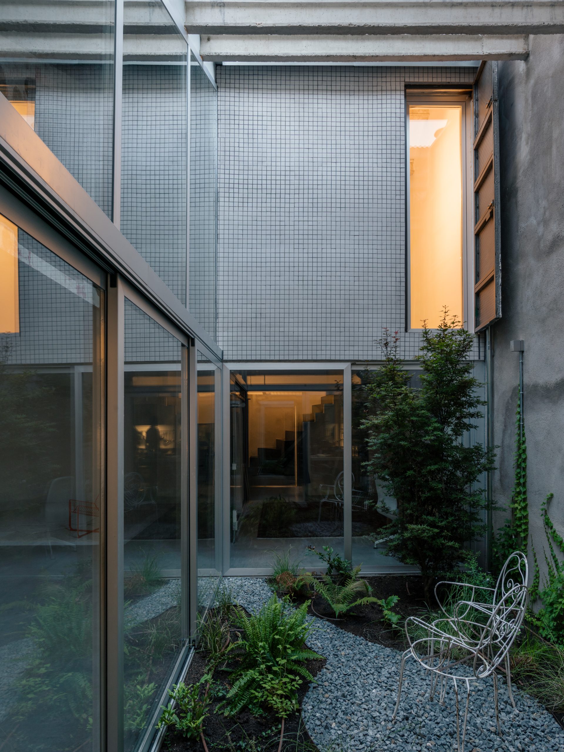 Planting occupies the compact courtyard enclosed by glazing.