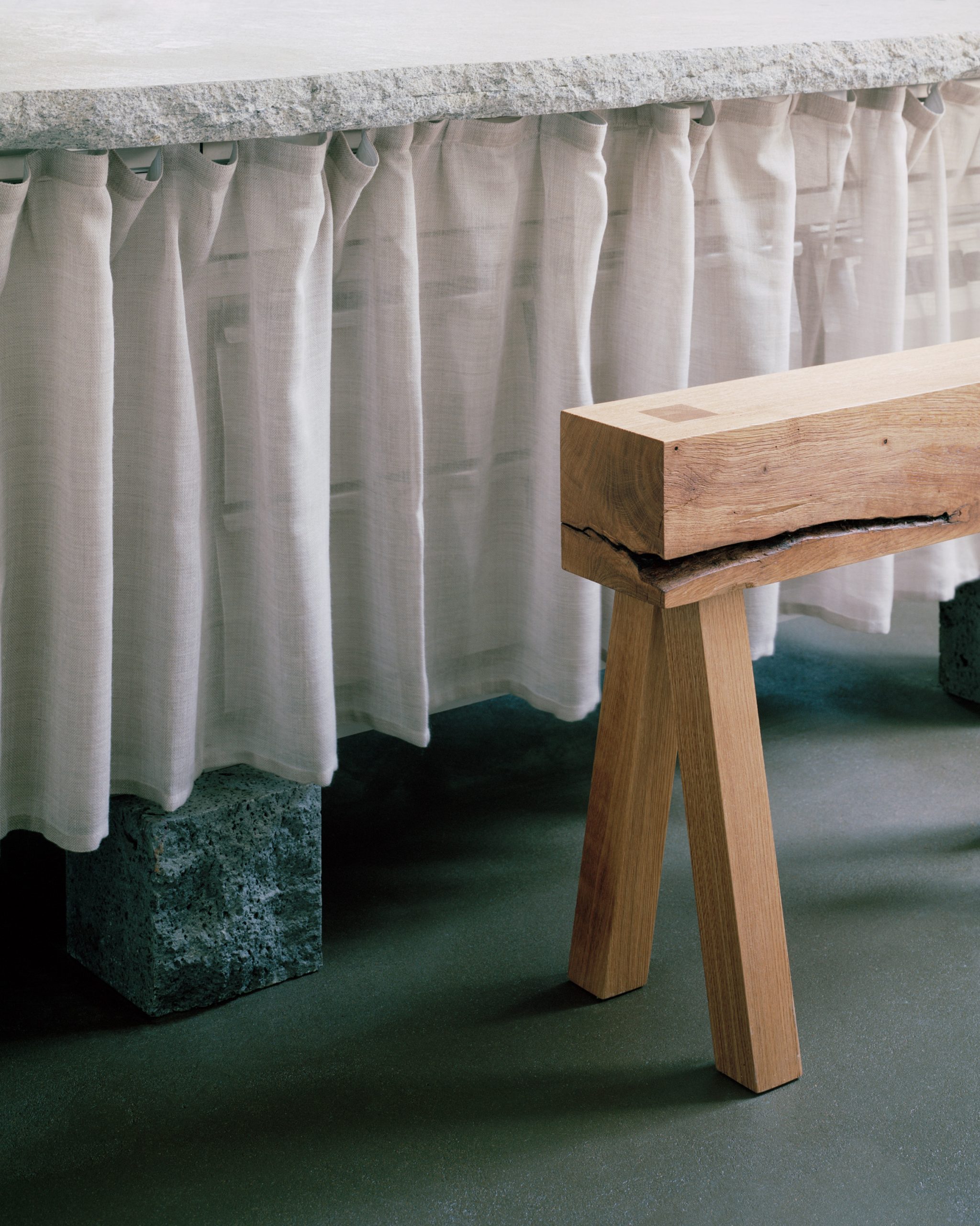 Detail of an oak table beside softly pleated hessian curtains