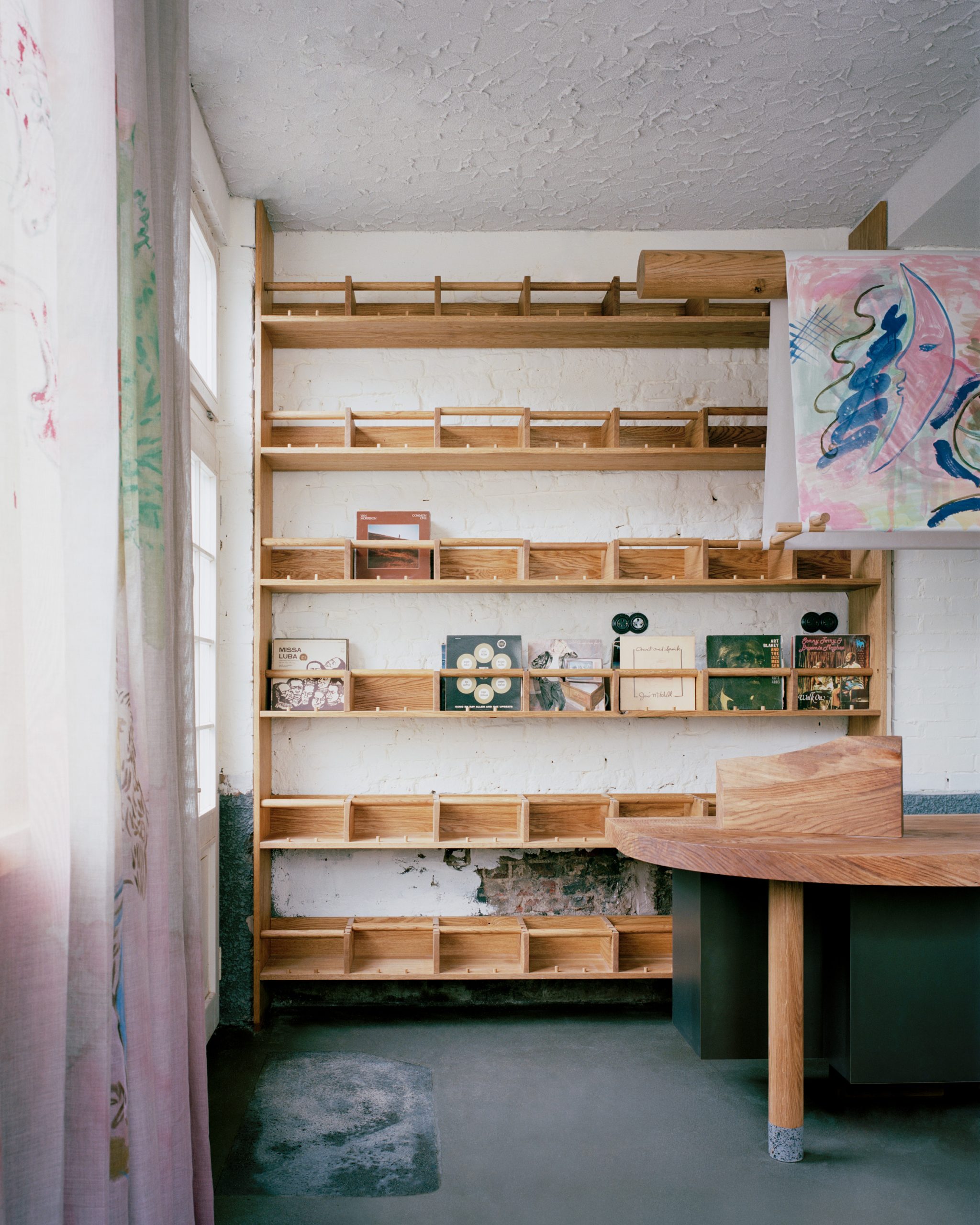 Custom oak shelving and furniture framed by painted hessian curtains