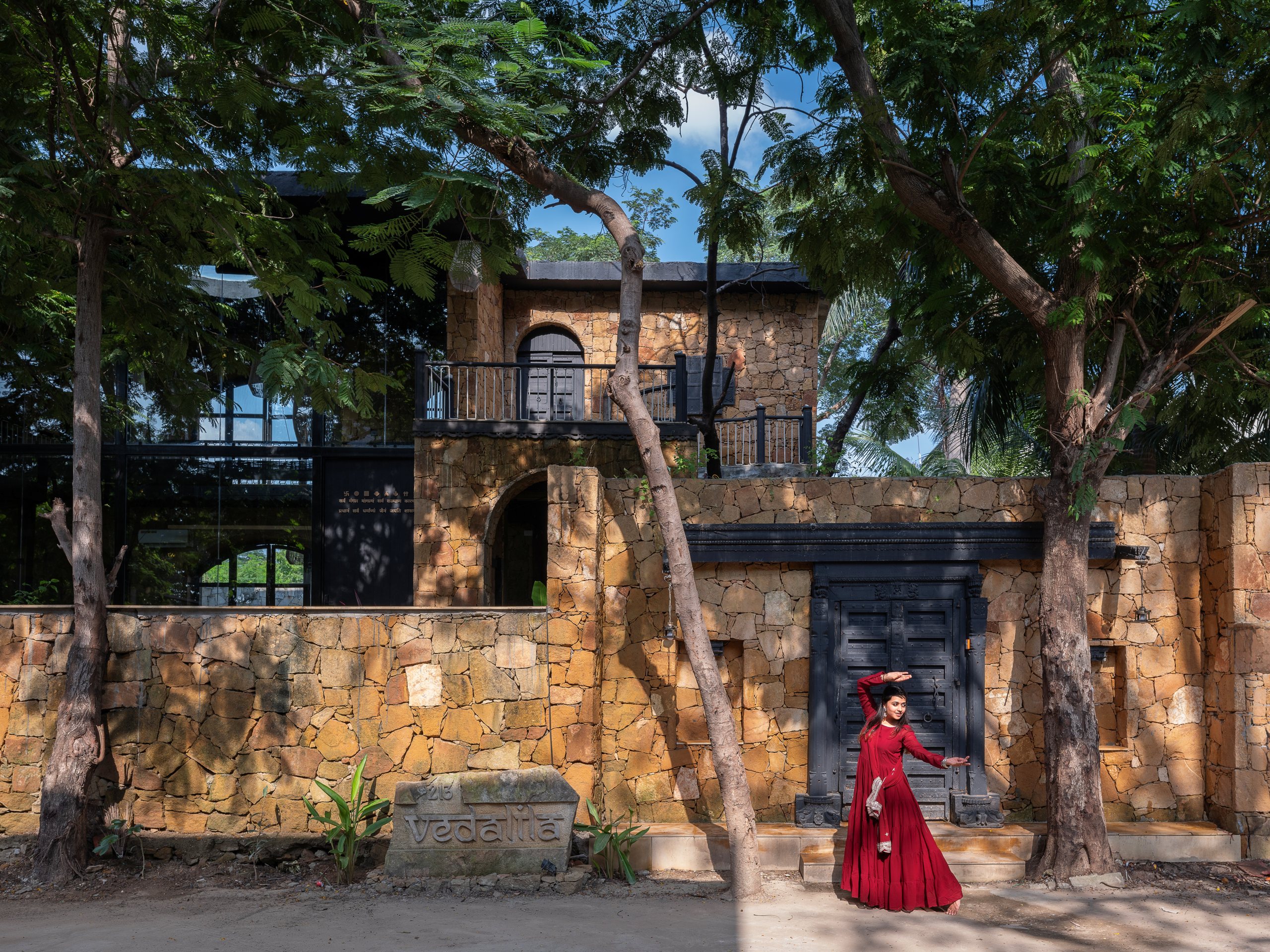 Sandstone facade of Vedalila house shaded by a mature neem tree