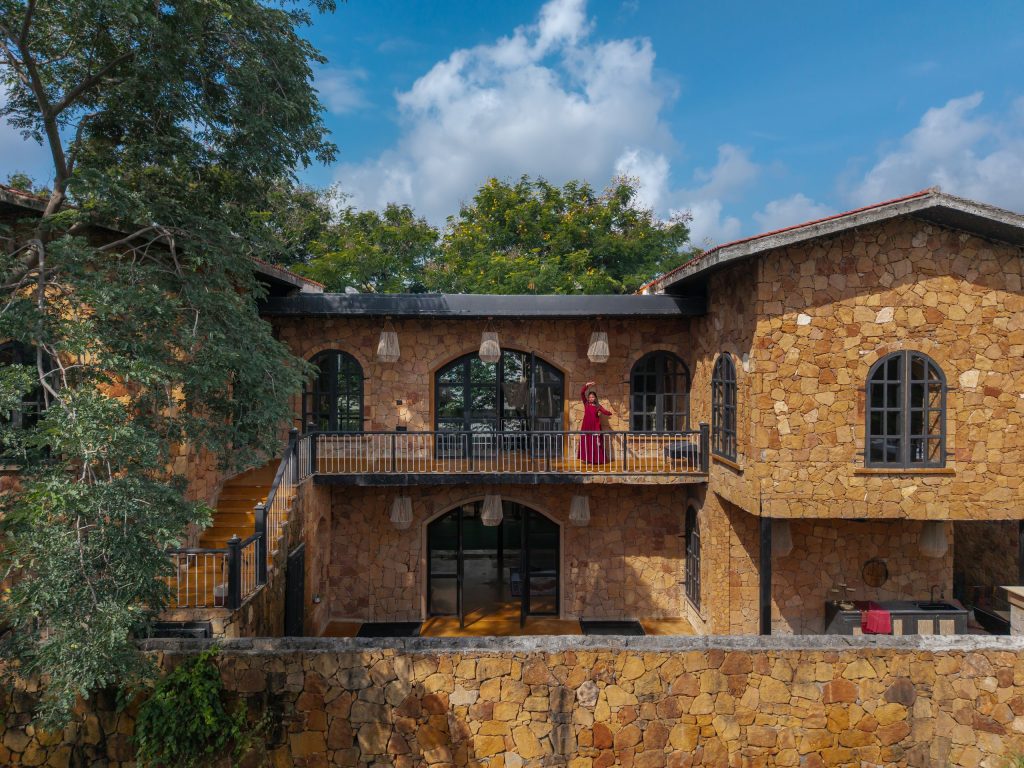 Rear sandstone facade, balcony and pool at Vedalila house