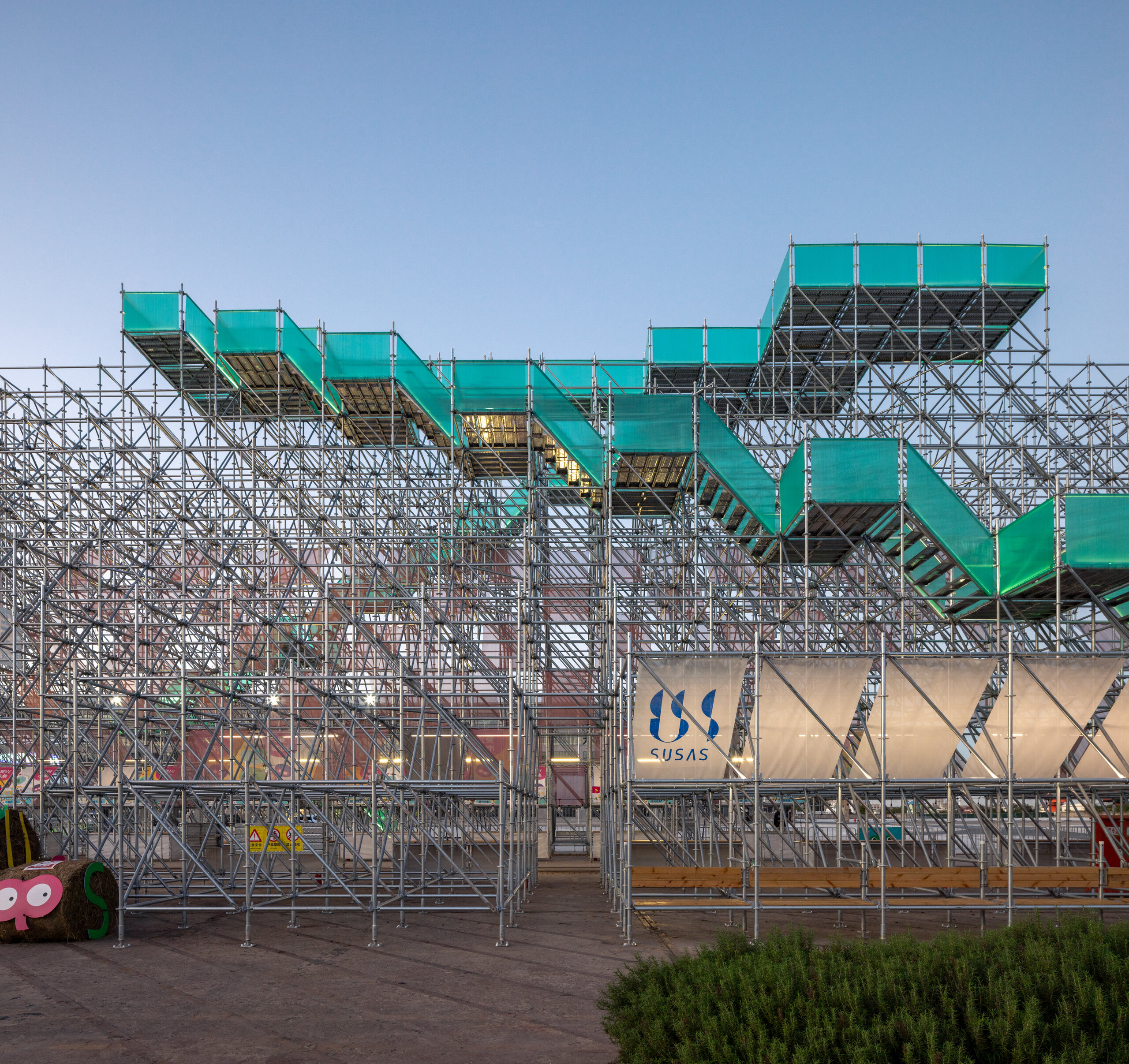 Green zigzag stairs climbing through the scaffolding frame