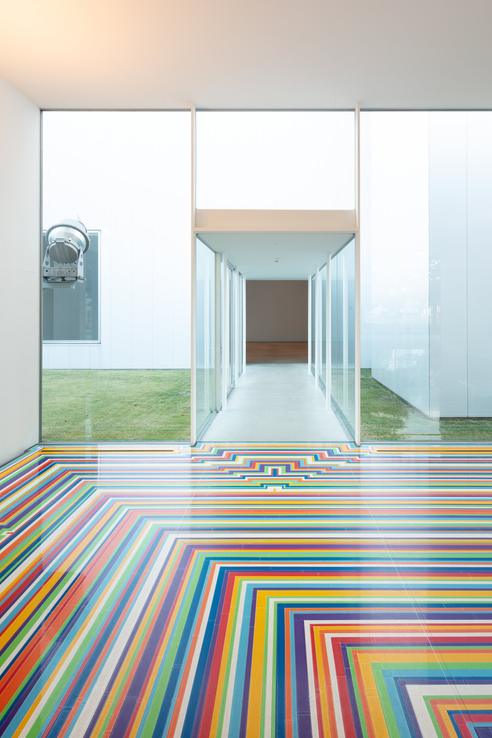 White gallery opening onto transparent corridors and grass courtyards