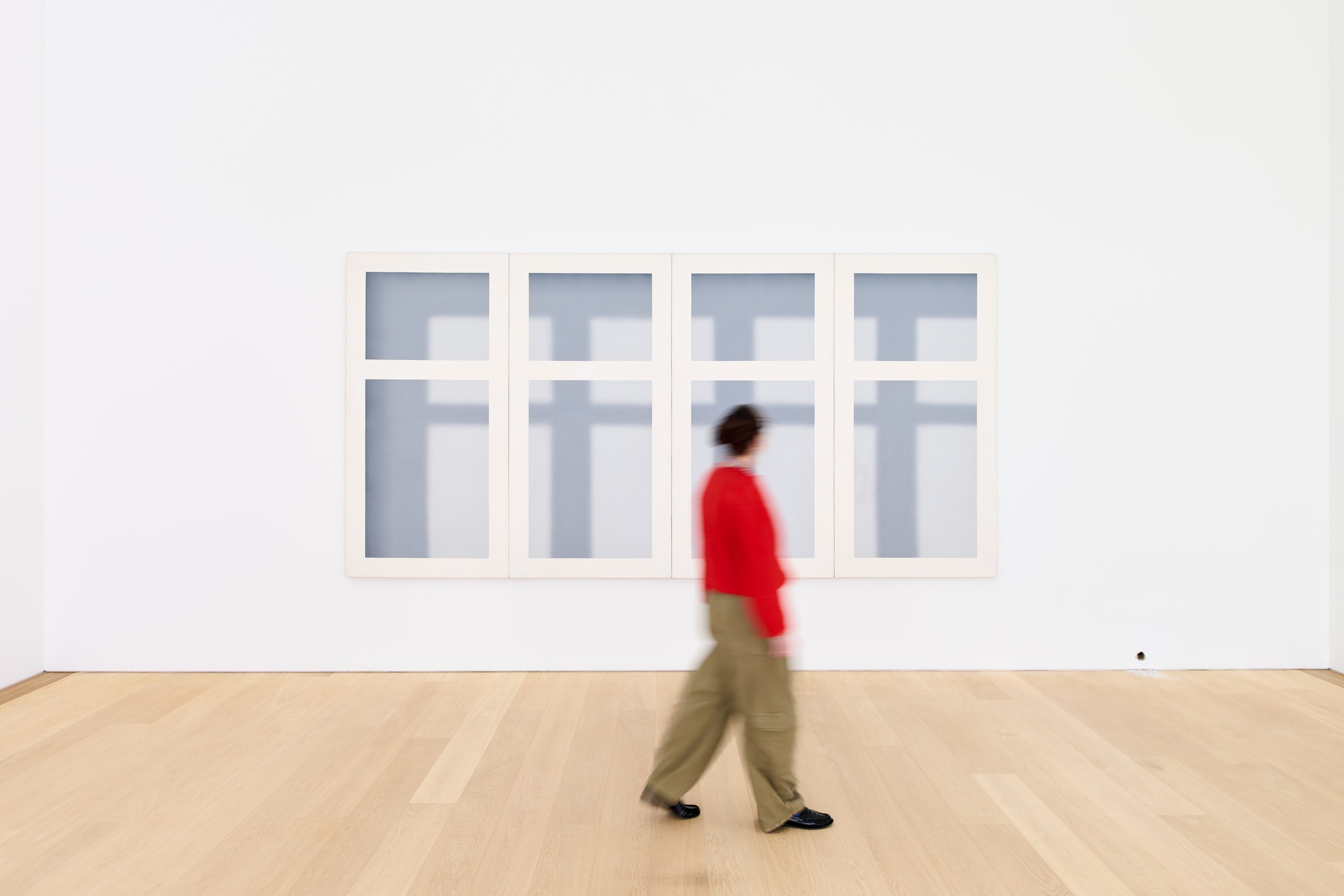 Visitor passing Gerhard Richter’s window image in a white gallery.