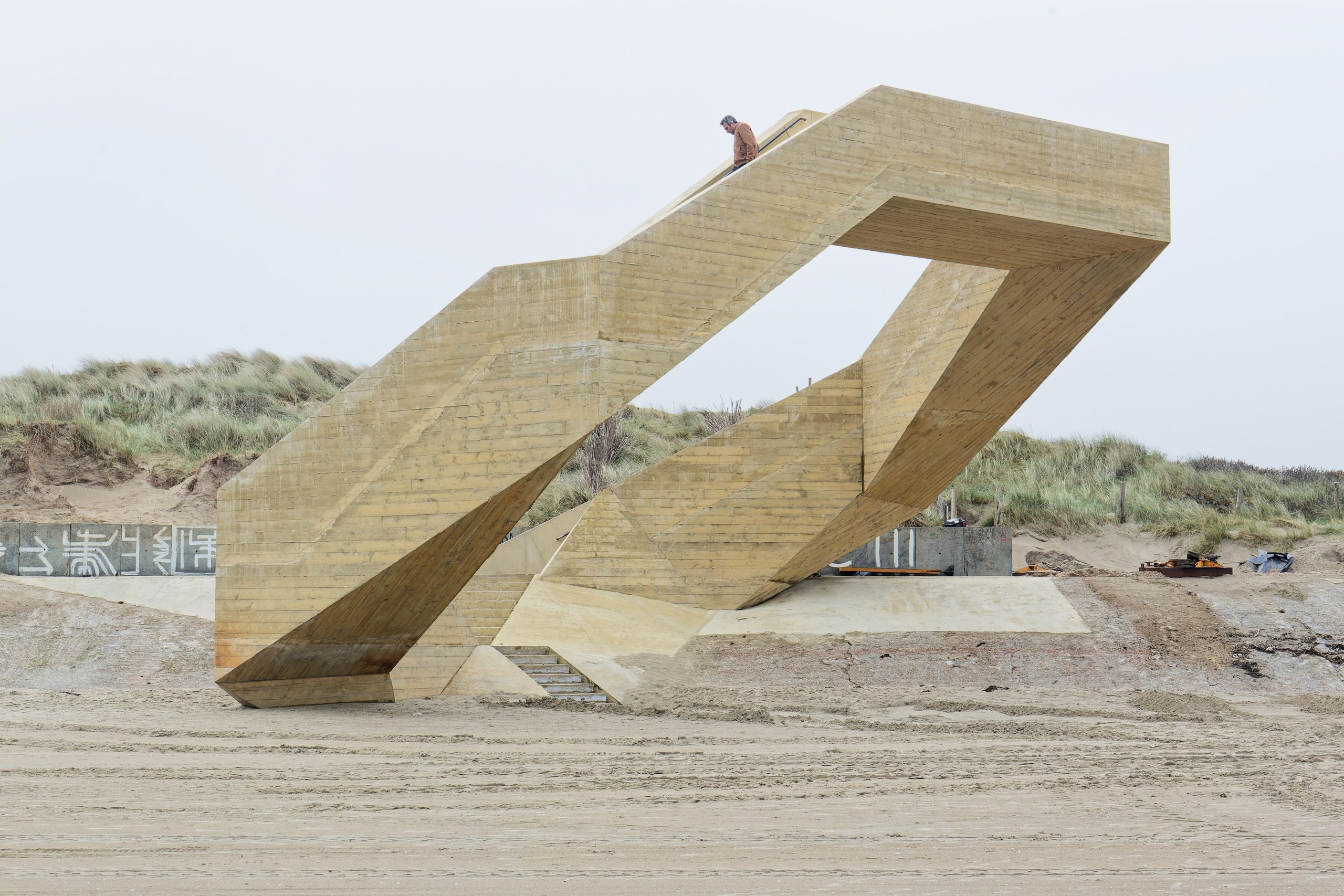 The elevated path rises above the sand before turning toward the sea.