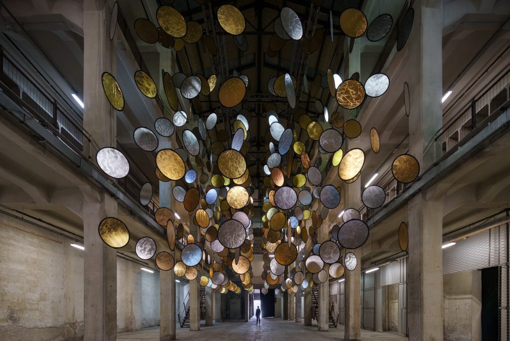 HALOS by SpY with gold and silver reflective circles suspended across a former railway factory in Florence