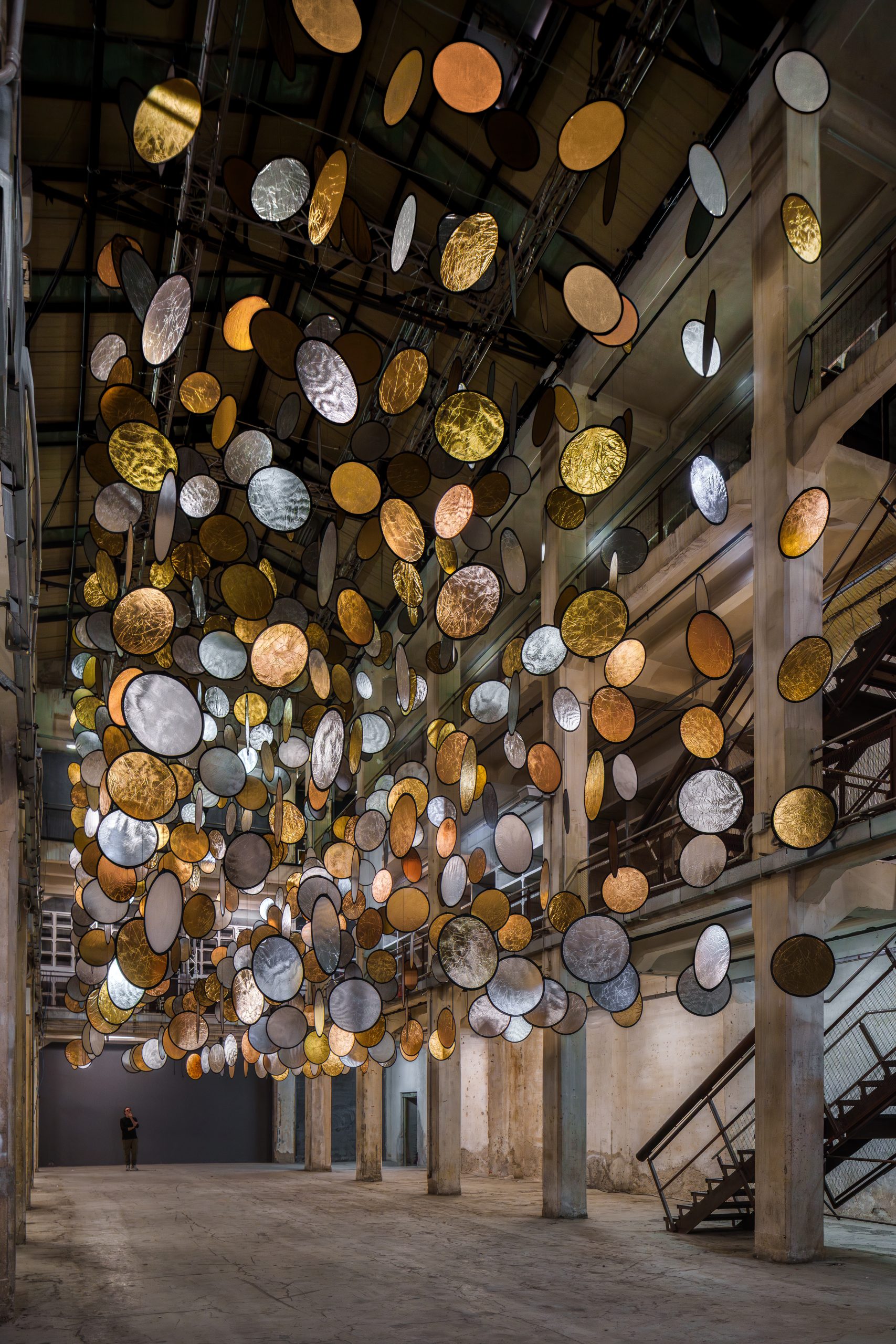 Side view of HALOS by SpY, with suspended reflective circles filling a three-level atrium