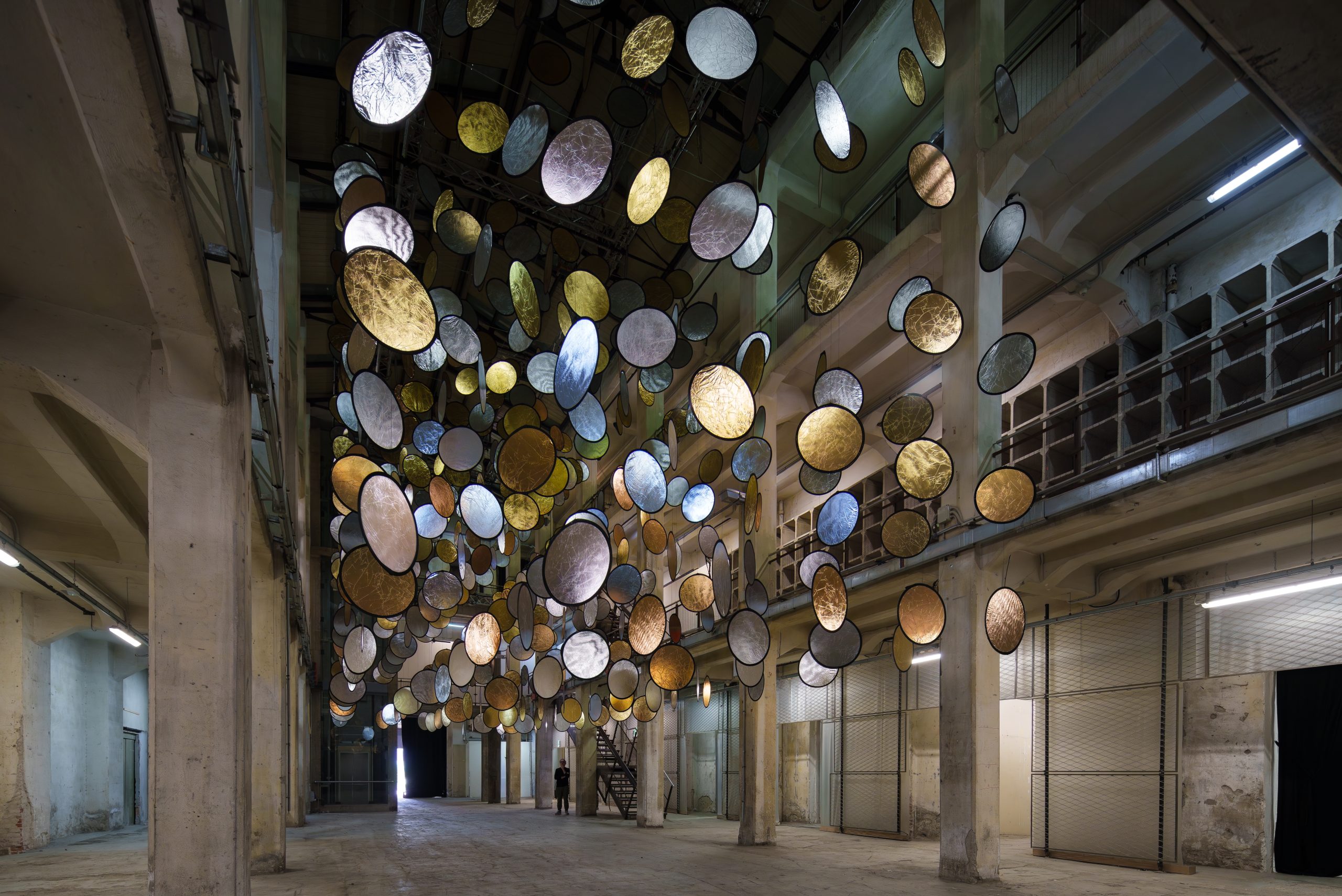 Wide view of HALOS between the concrete columns and upper walkways of a former railway factory