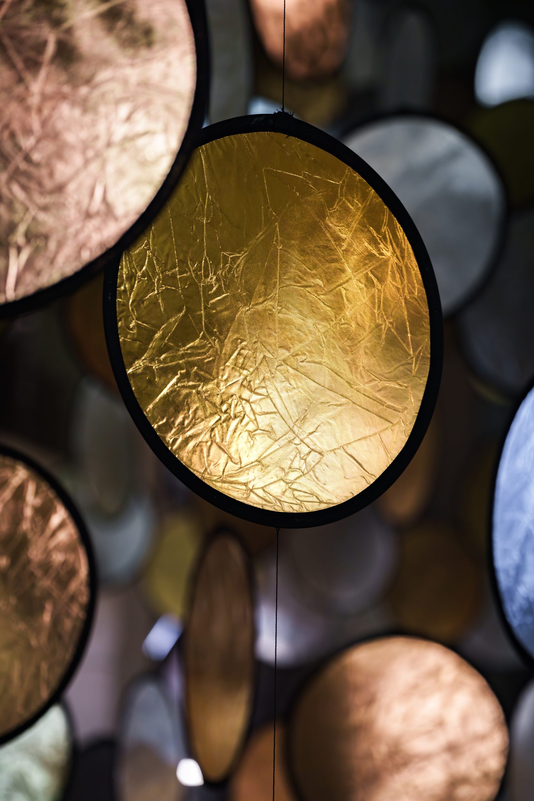 Close-up of a gold-toned reflective disc in SpY's HALOS installation