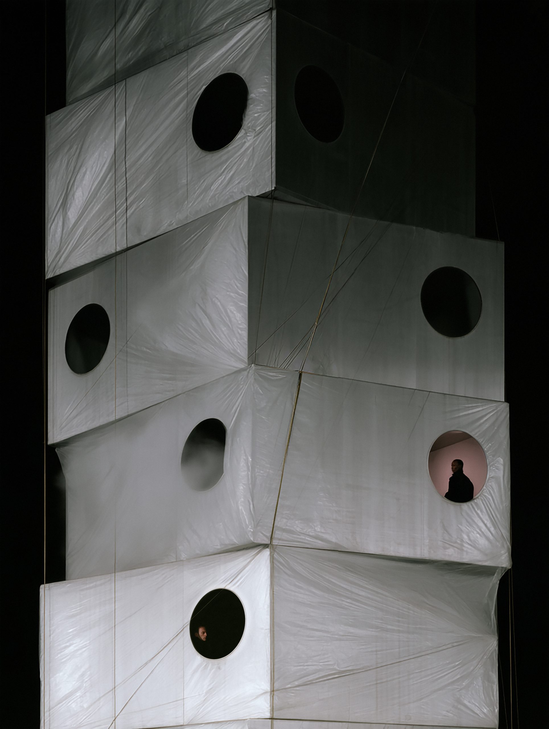 Stacked white volumes with round openings and isolated inhabitants in MóDULO De ViDA