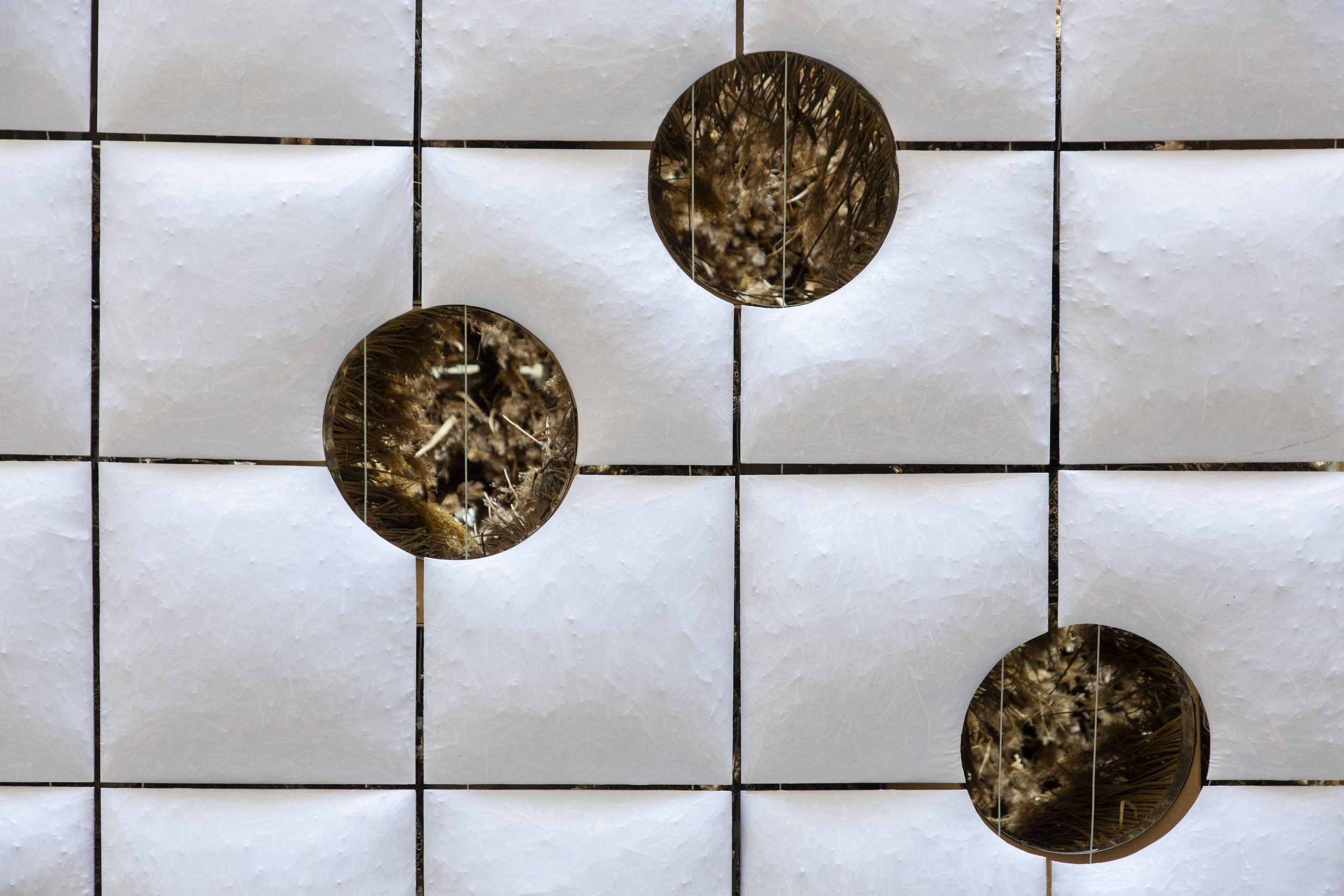 Grid of reed-filled pillows with circular viewing openings