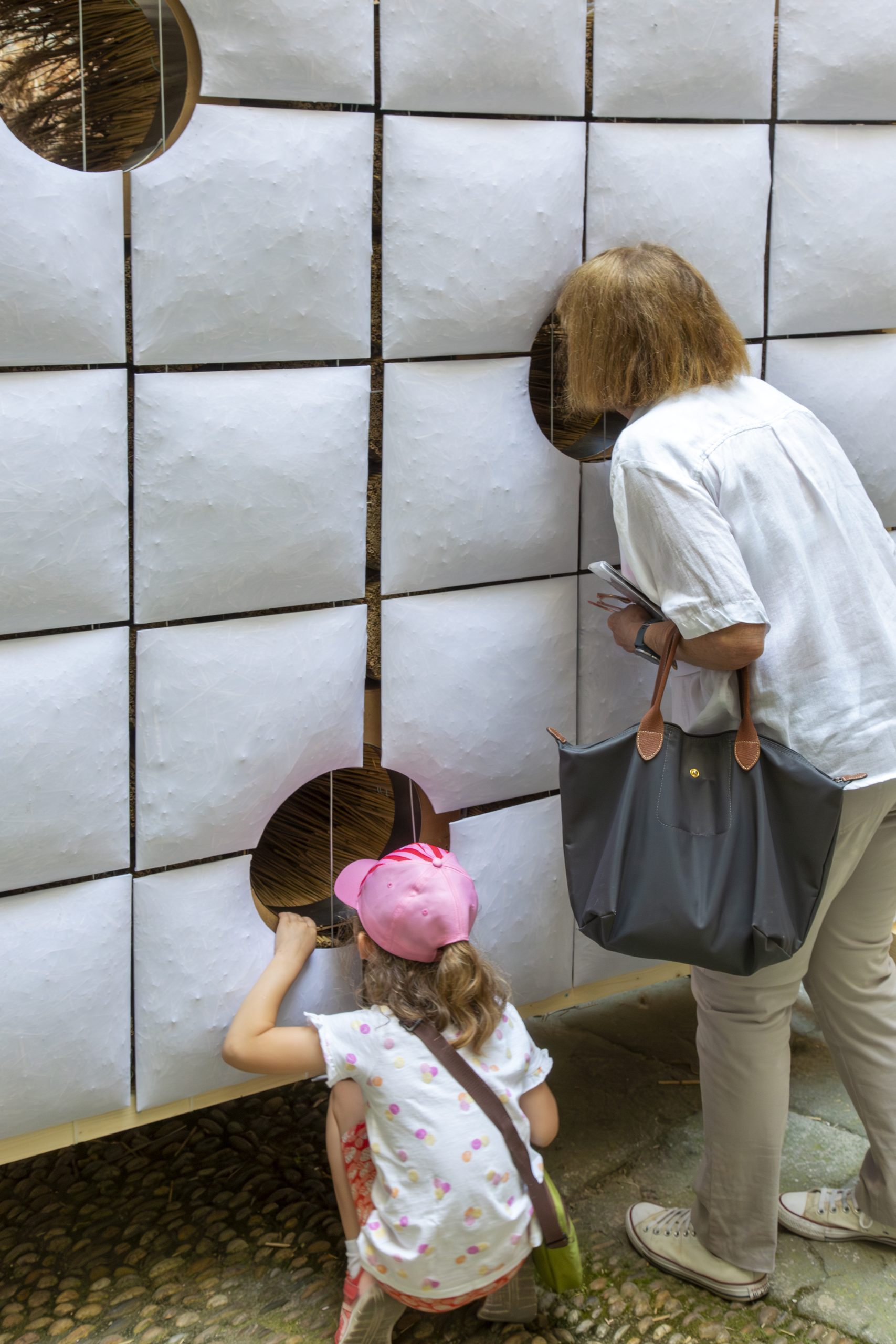 Visitors looking through openings in the padded facade
