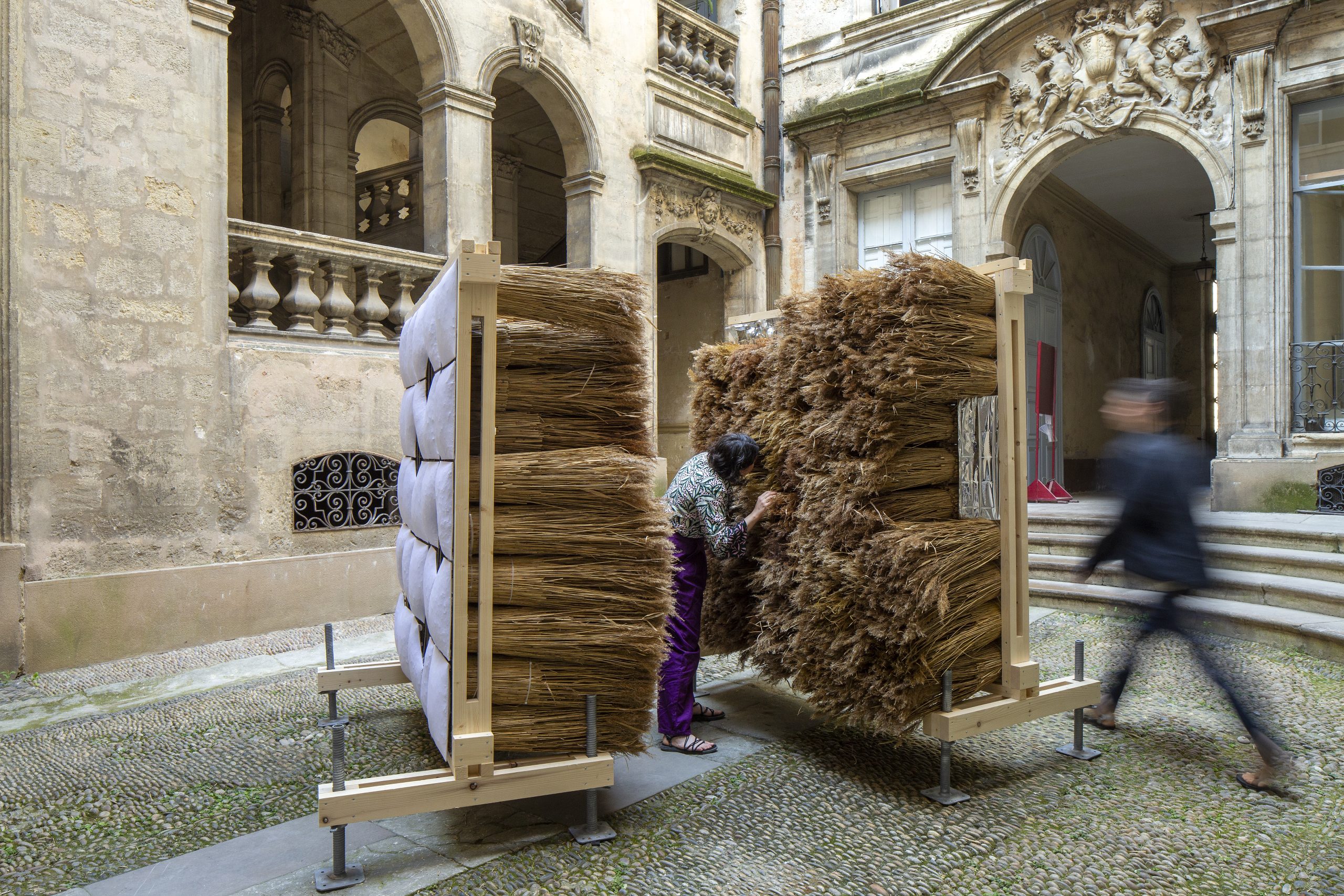 Two freestanding reed walls and visitors in the Montpellier courtyard