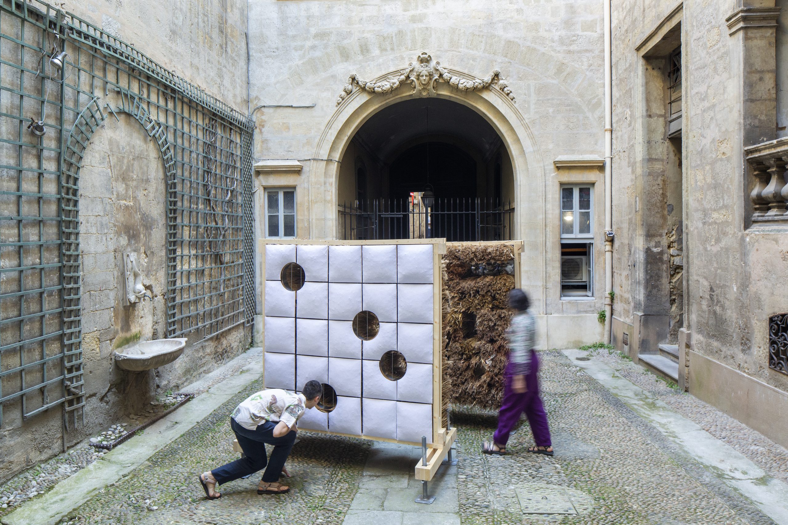 Visitor crouching to look through a low circular opening